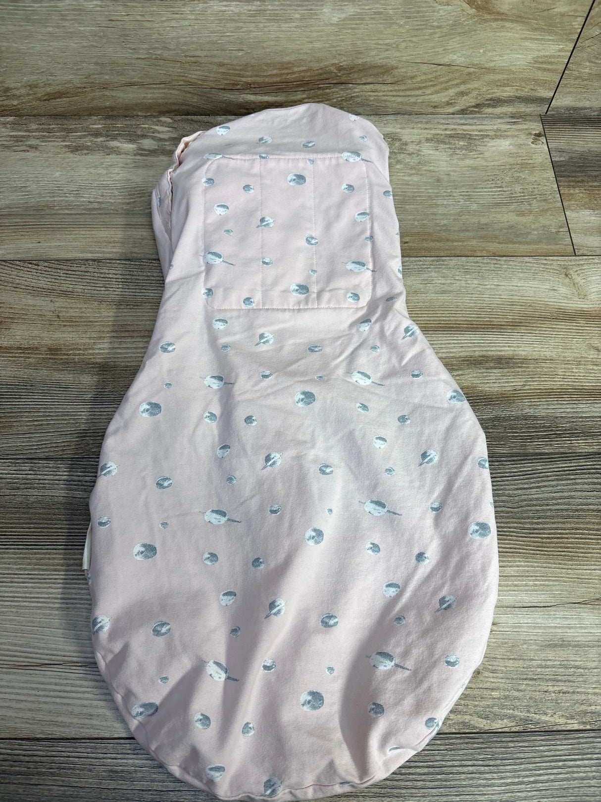 Pink baby swaddle with blue polka dots on wood floor, soft cotton fabric