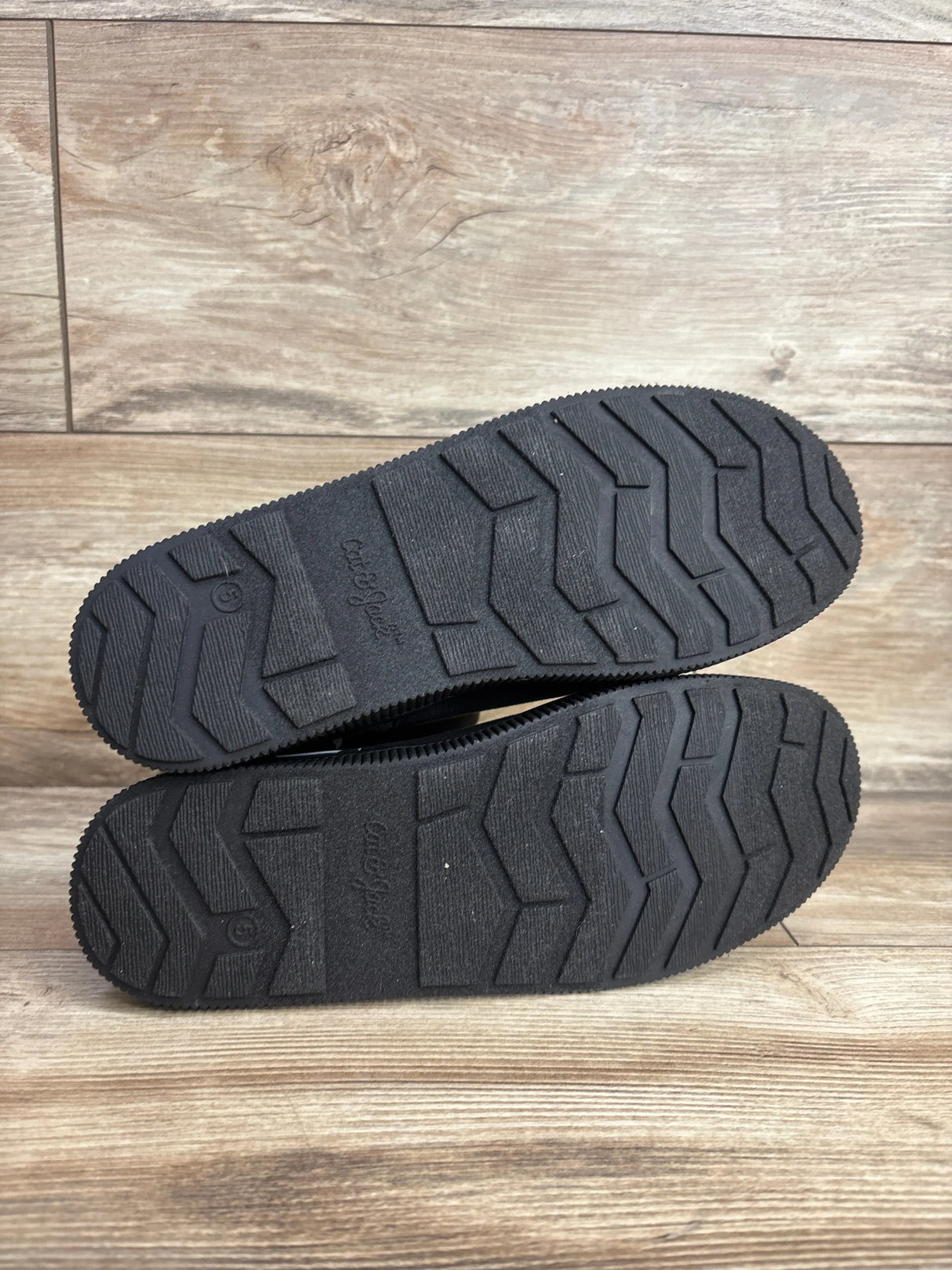 Close-up of Cat and Jack Holland shearling boots size 5Y showing black rubber soles with zigzag tread on wood floor