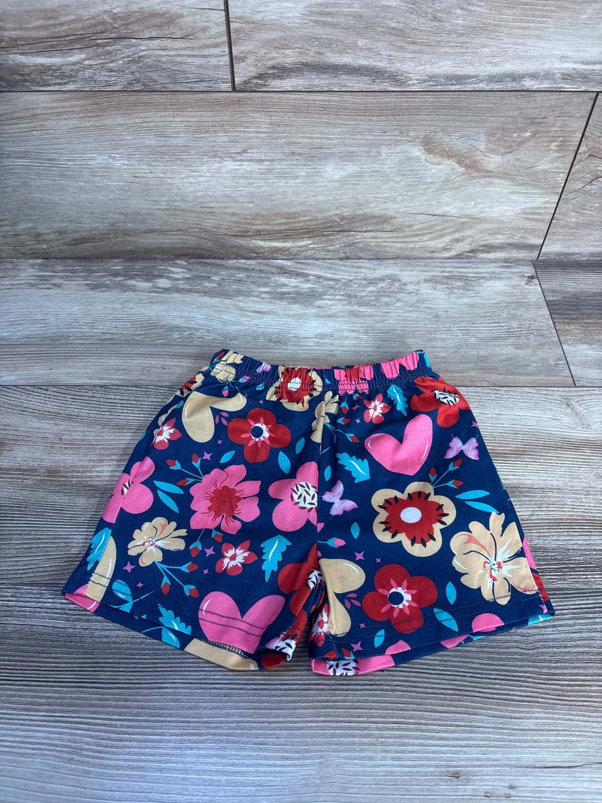 Front view of navy floral pull-on shorts showcasing elastic waistband and floral print on a wood-look floor