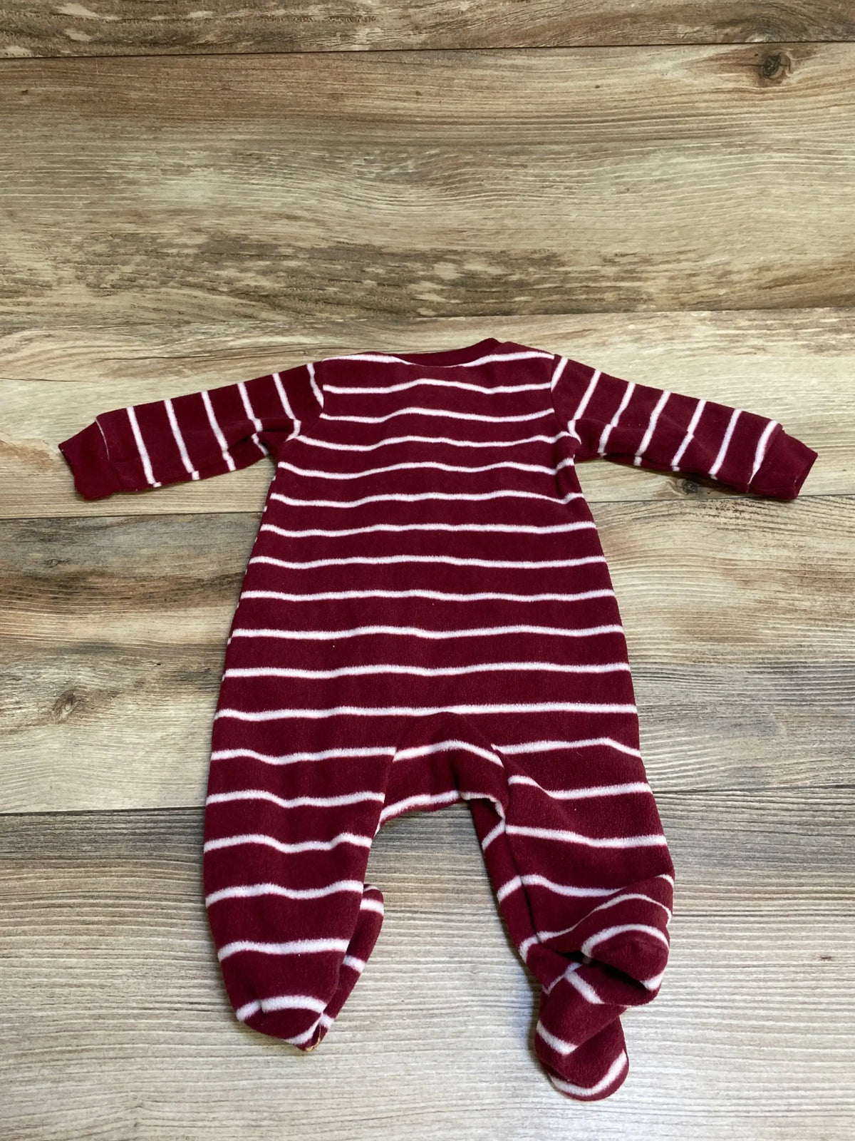 Maroon and white striped baby sleeper with footies on wooden background