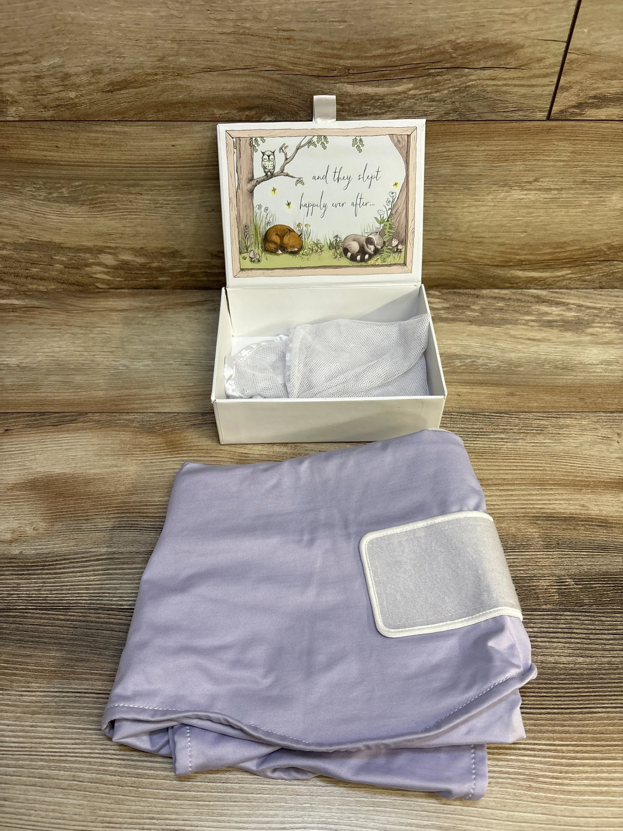 Lavender baby swaddle blanket next to open gift box with woodland animal design