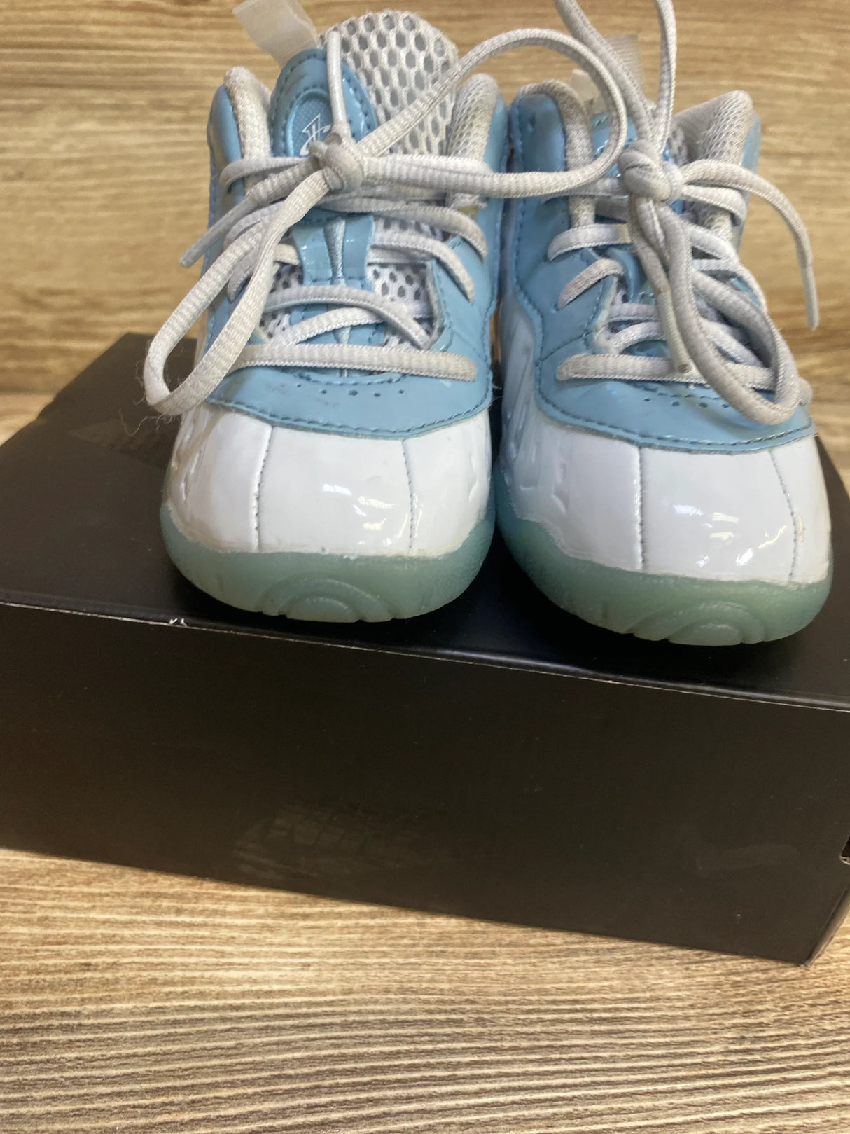 Front view of toddler Nike Little Posite One in light blue and white showing patent toe, mesh tongue, laces on black shoebox