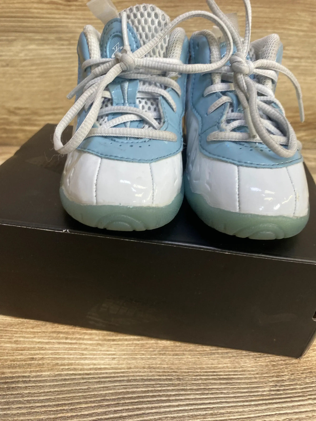 Front view of toddler Nike Little Posite One in light blue and white showing patent toe, mesh tongue, laces on black shoebox