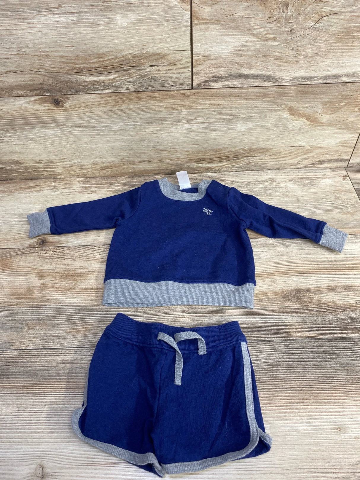 Blue and gray toddler sweatshirt and shorts set for kids, laid flat on wood floor.