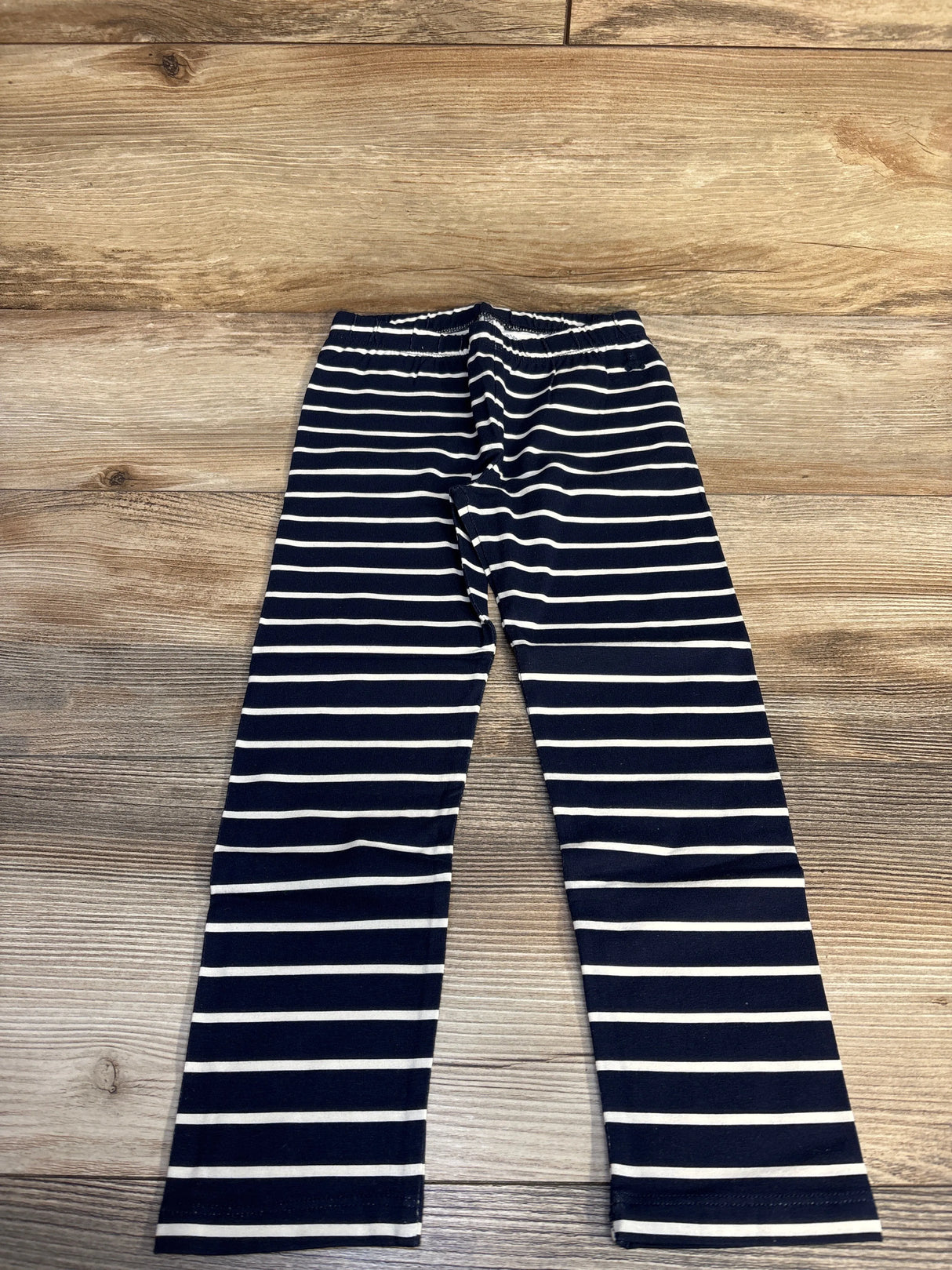 Navy blue and white striped leggings on wooden floor background
