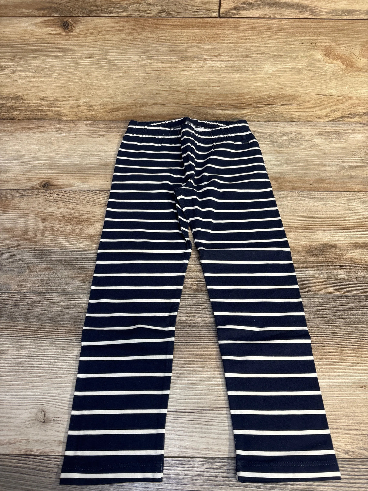 Navy blue and white striped leggings on wooden floor background