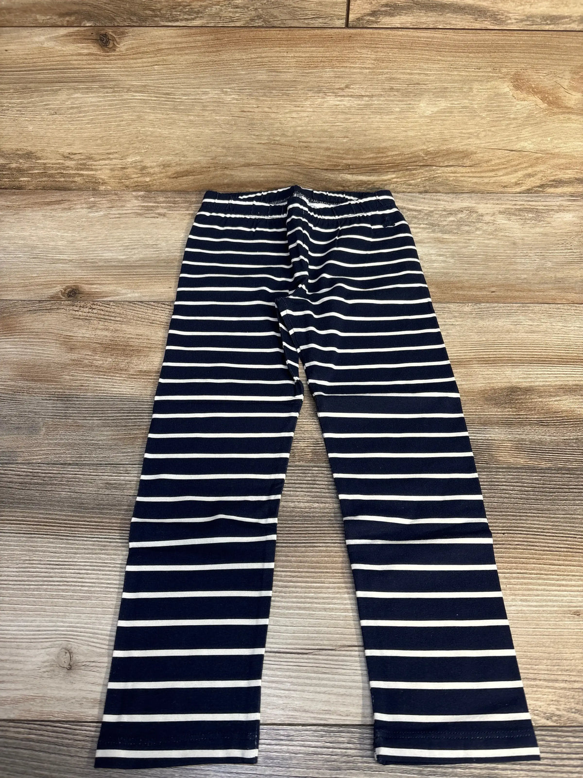 Navy blue and white striped leggings on wooden floor background