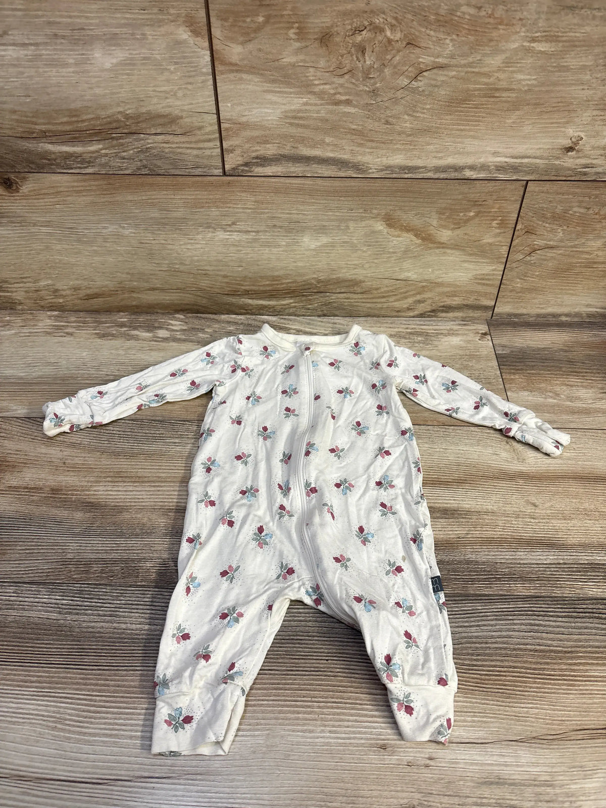 Front view of beige Modern Moments floral viscose sleeper showcasing long sleeves and zip front on a wood floor