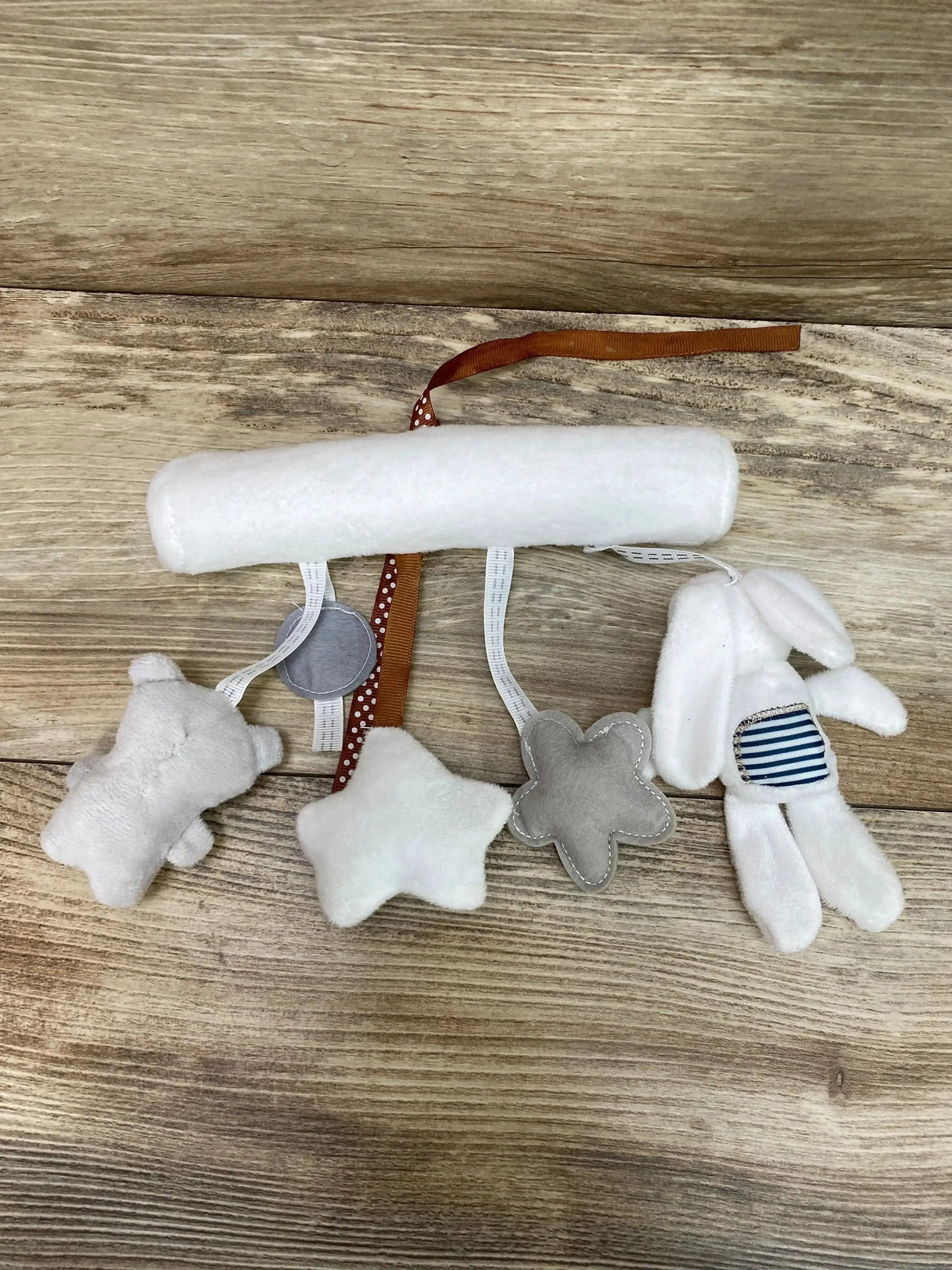 Front view of white hanging plush rabbit/bear music toy with hanging loop and stitched face on plain background