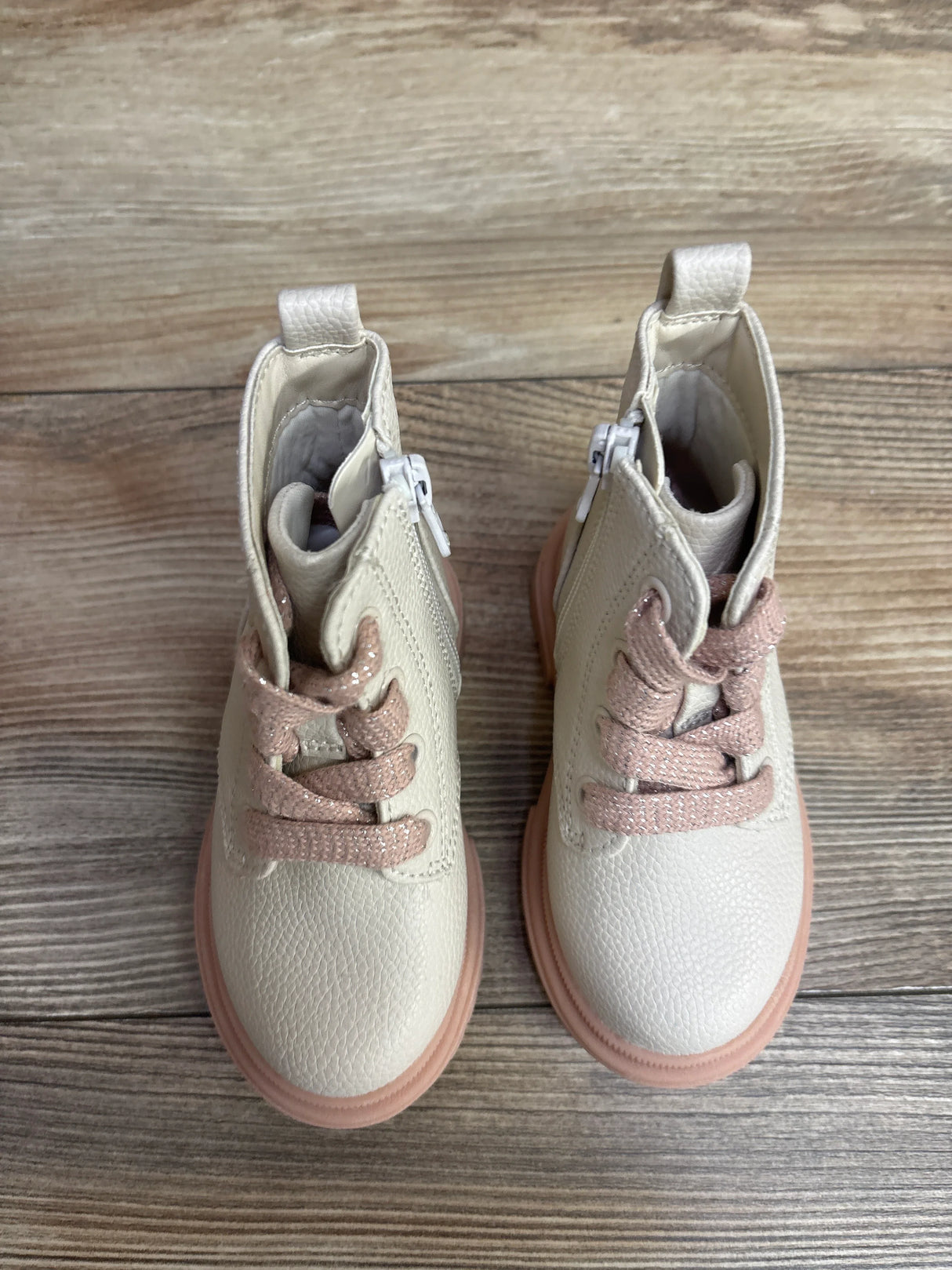 Pair of toddler cream-colored boots with pink laces and rubber soles on wood floor