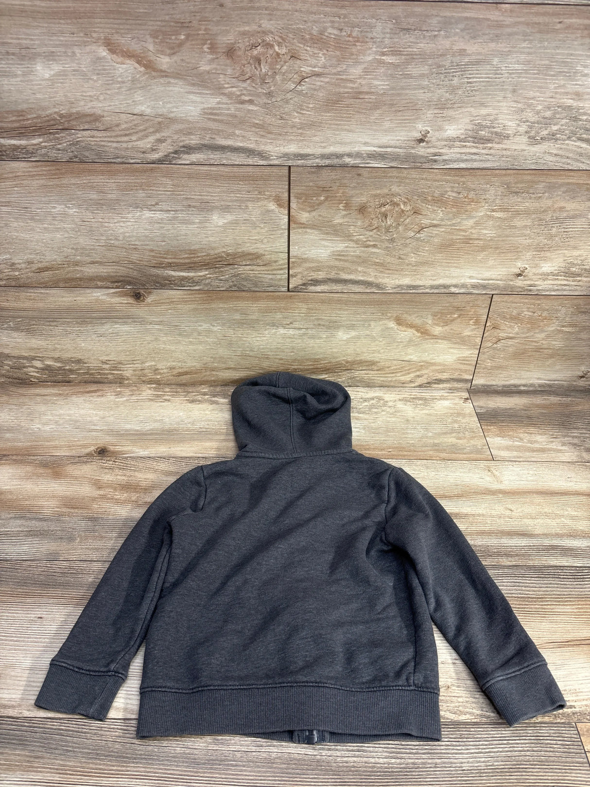 Dark gray children's hoodie laid flat on light wooden floor background
