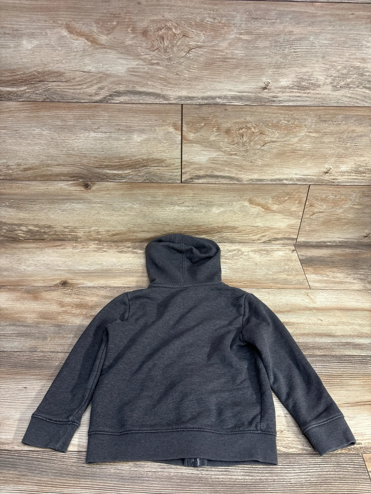Dark gray children's hoodie laid flat on light wooden floor background
