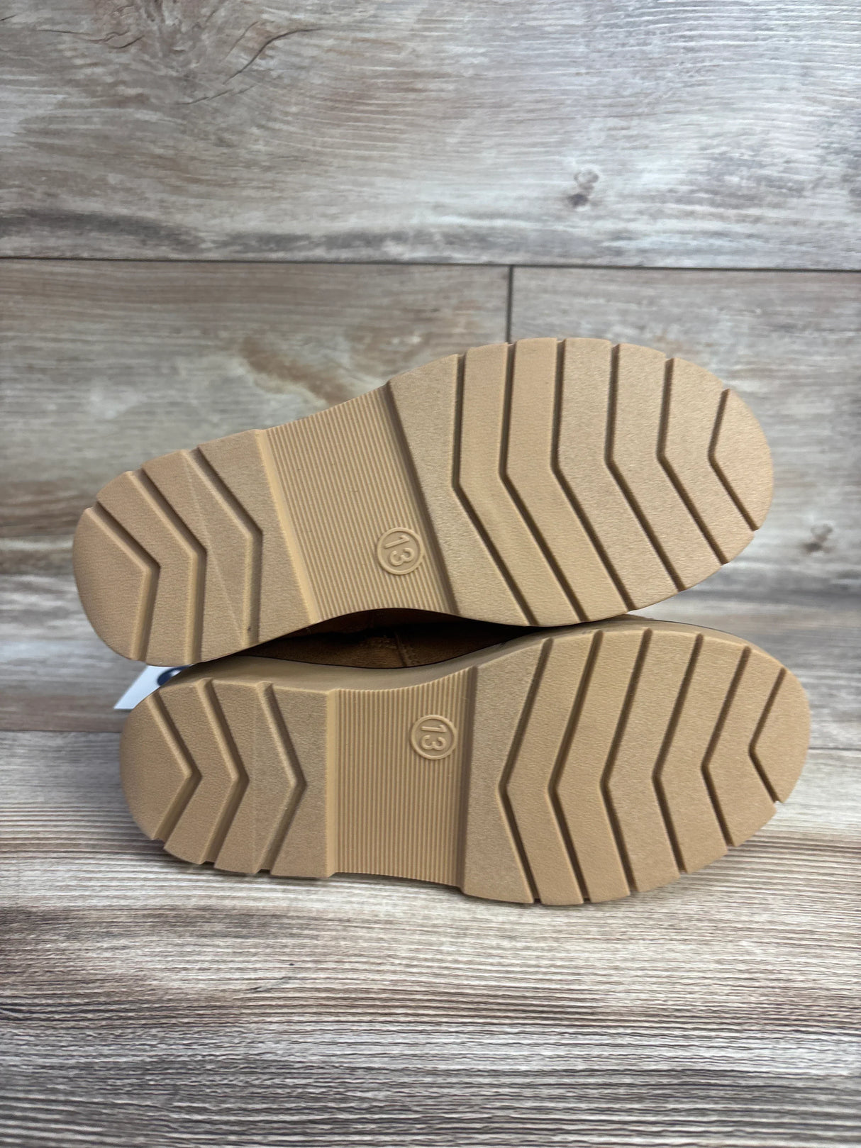 Kids tan rubber shoe soles with size 13, non-slip tread pattern on wood background