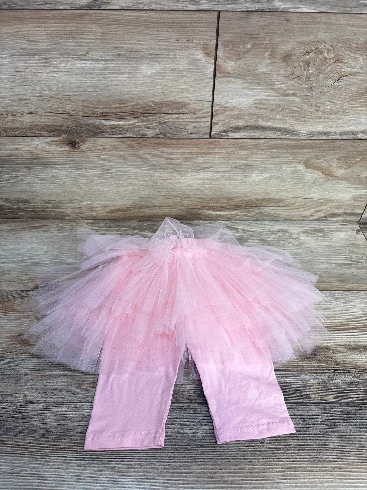 Pink baby tutu pants with tulle skirt on wooden floor background