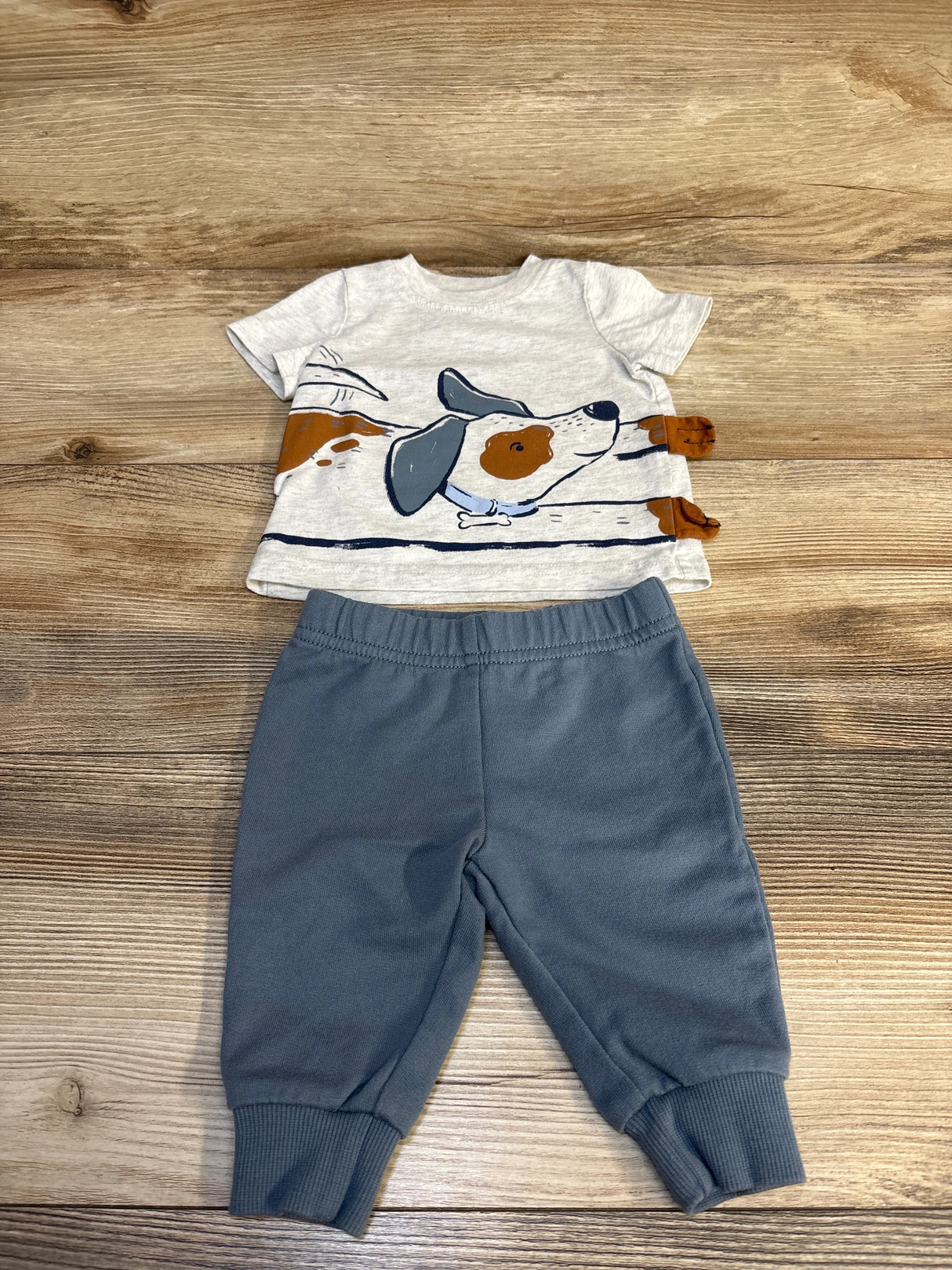 Baby outfit with dog graphic t-shirt and blue jogger pants on wooden background
