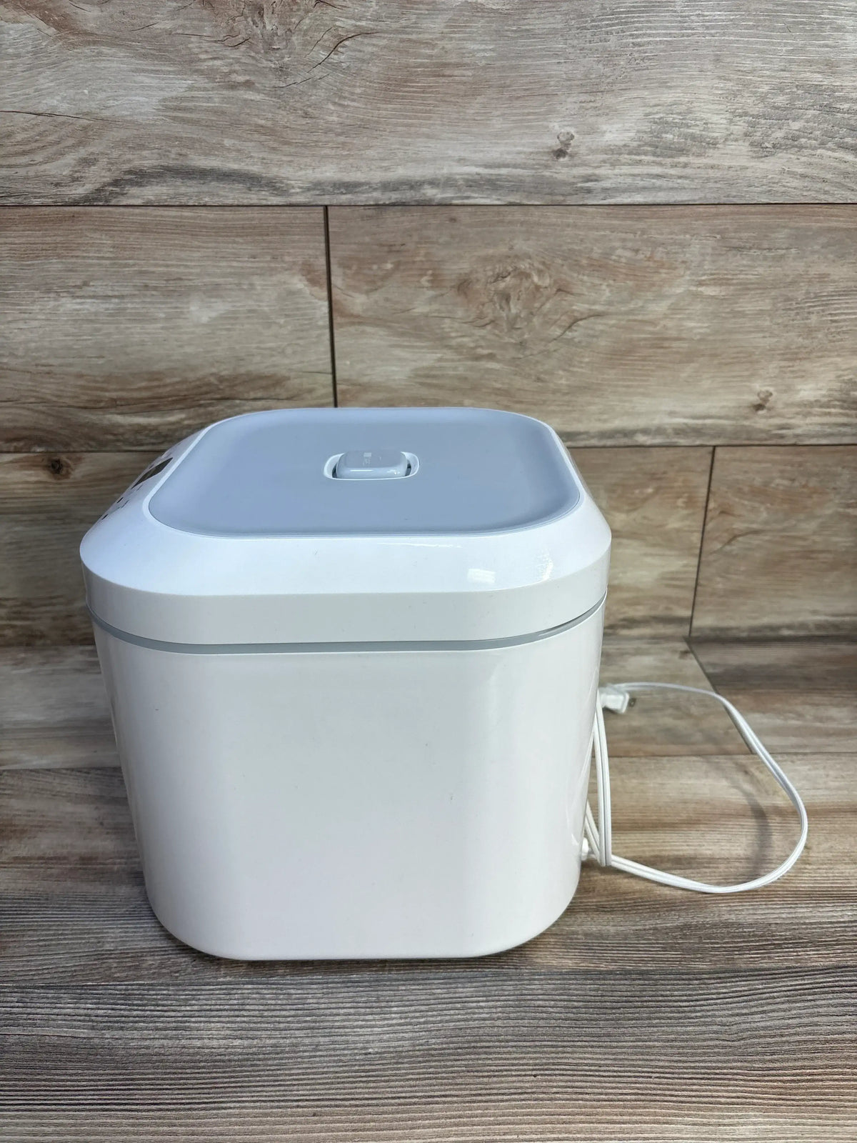 Front view of UV Care Multipurpose Sterilizer Lite 1 showcasing its closed lid and power cord on a wood background