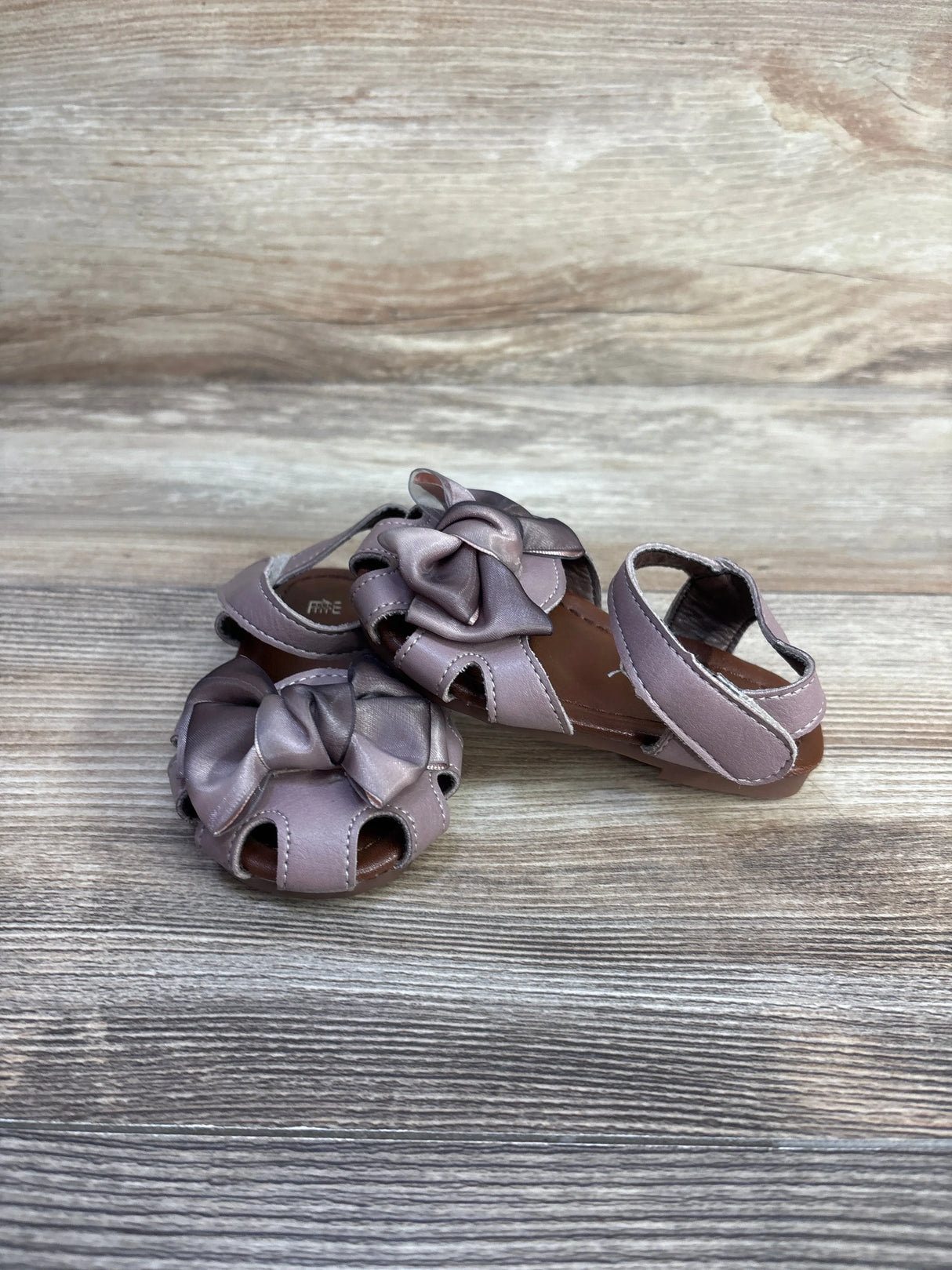 Front and side view of mauve EYY baby sandals, size 5C, showing bow detail and open-toe cutouts on wood-grain background