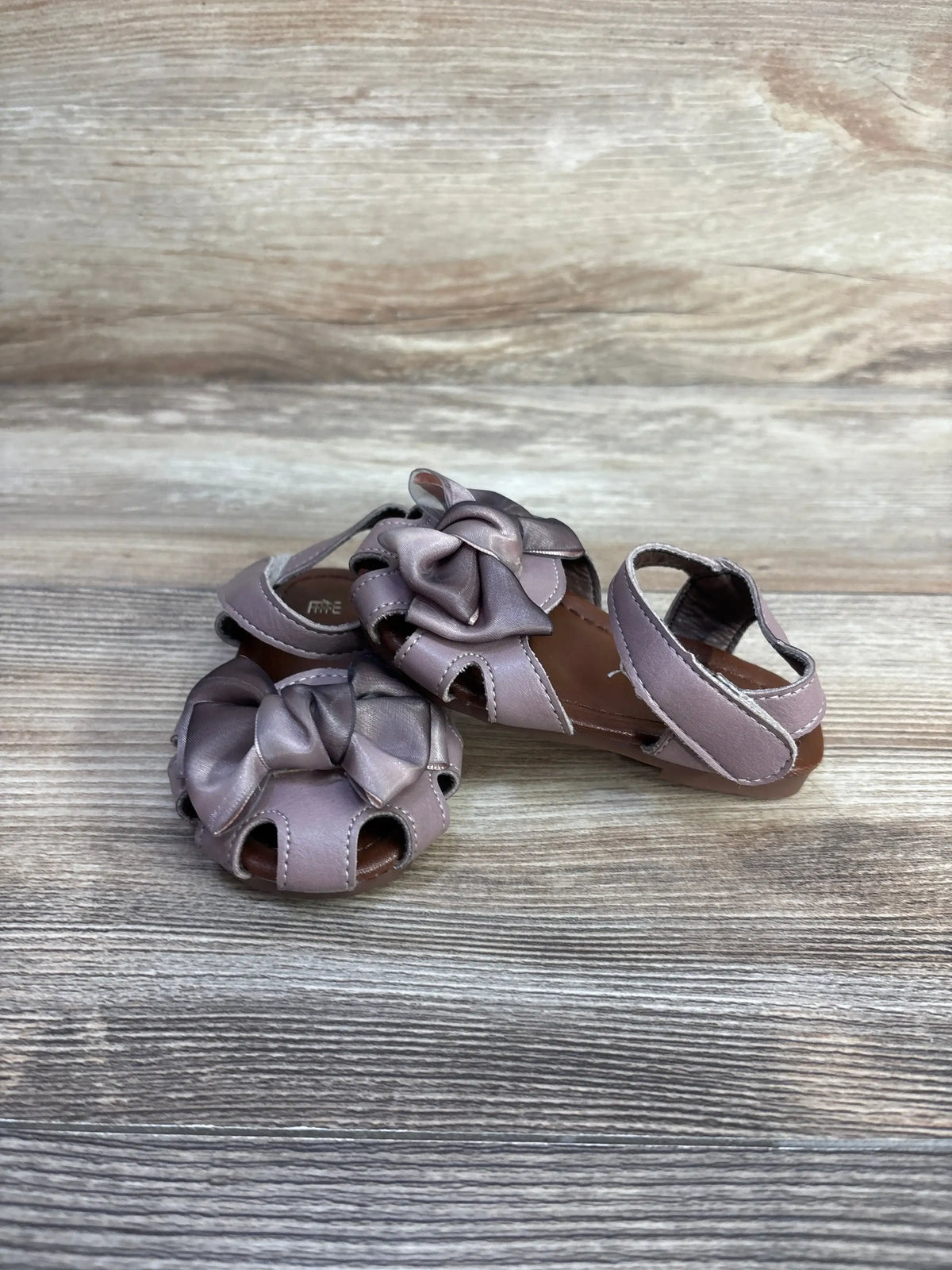 Front and side view of mauve EYY baby sandals, size 5C, showing bow detail and open-toe cutouts on wood-grain background