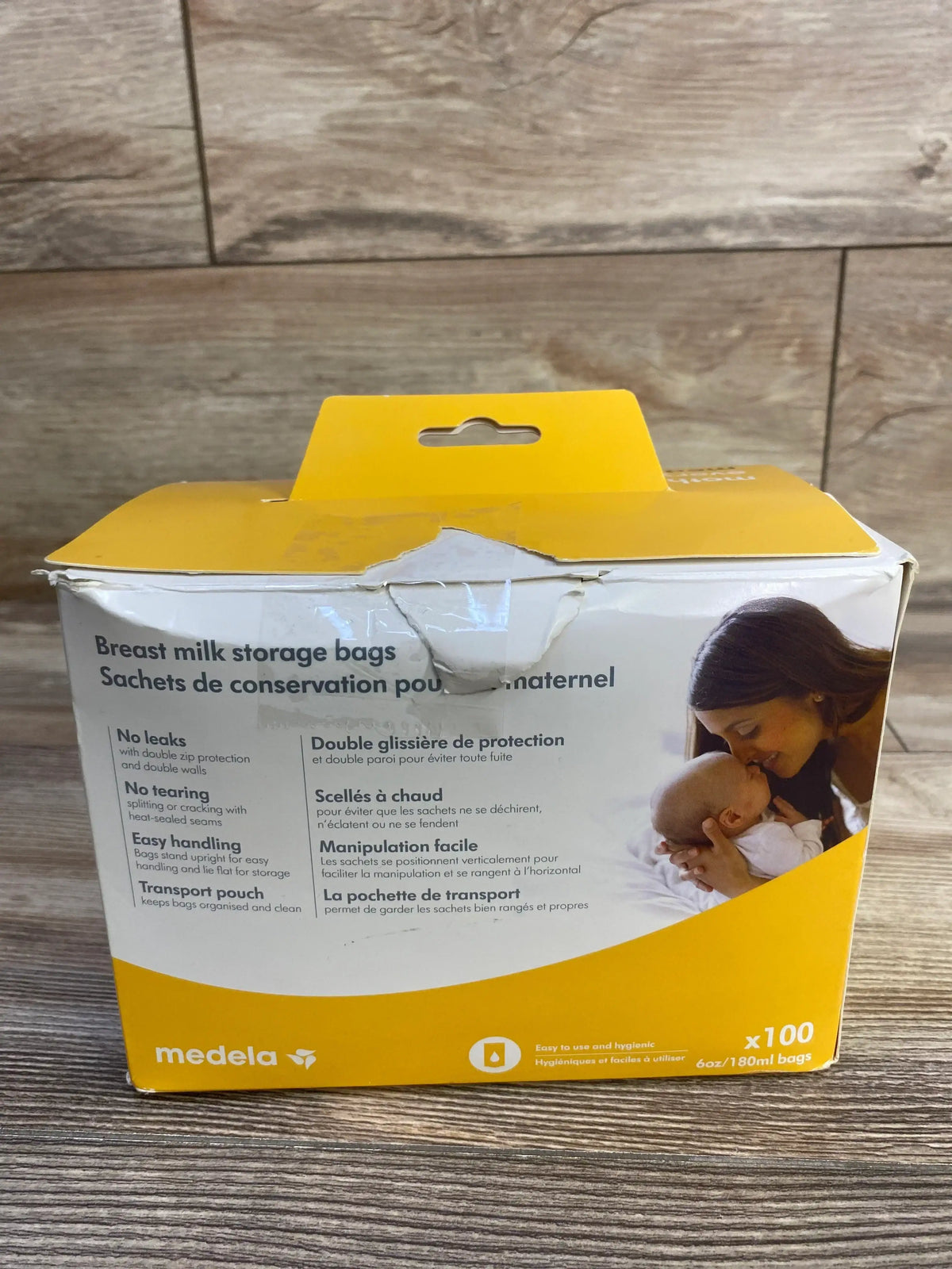 Front view of Medela breast milk storage bags box showing product name and benefits text, 100 count yellow-and-white packaging on wood surface