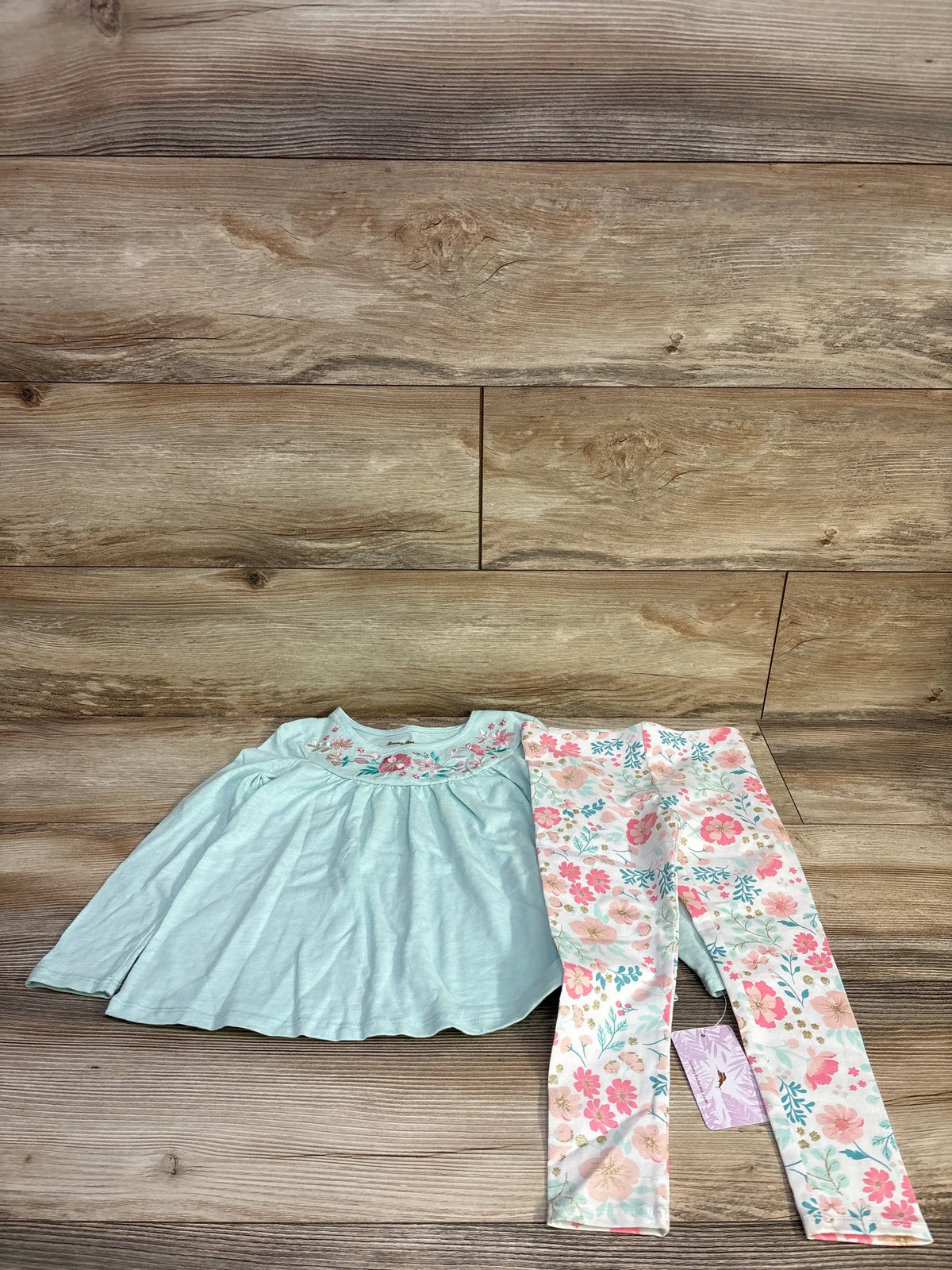 Front view of Tommy Bahama aqua two-piece set in size 4T showcasing embroidered top and floral leggings on wood planks