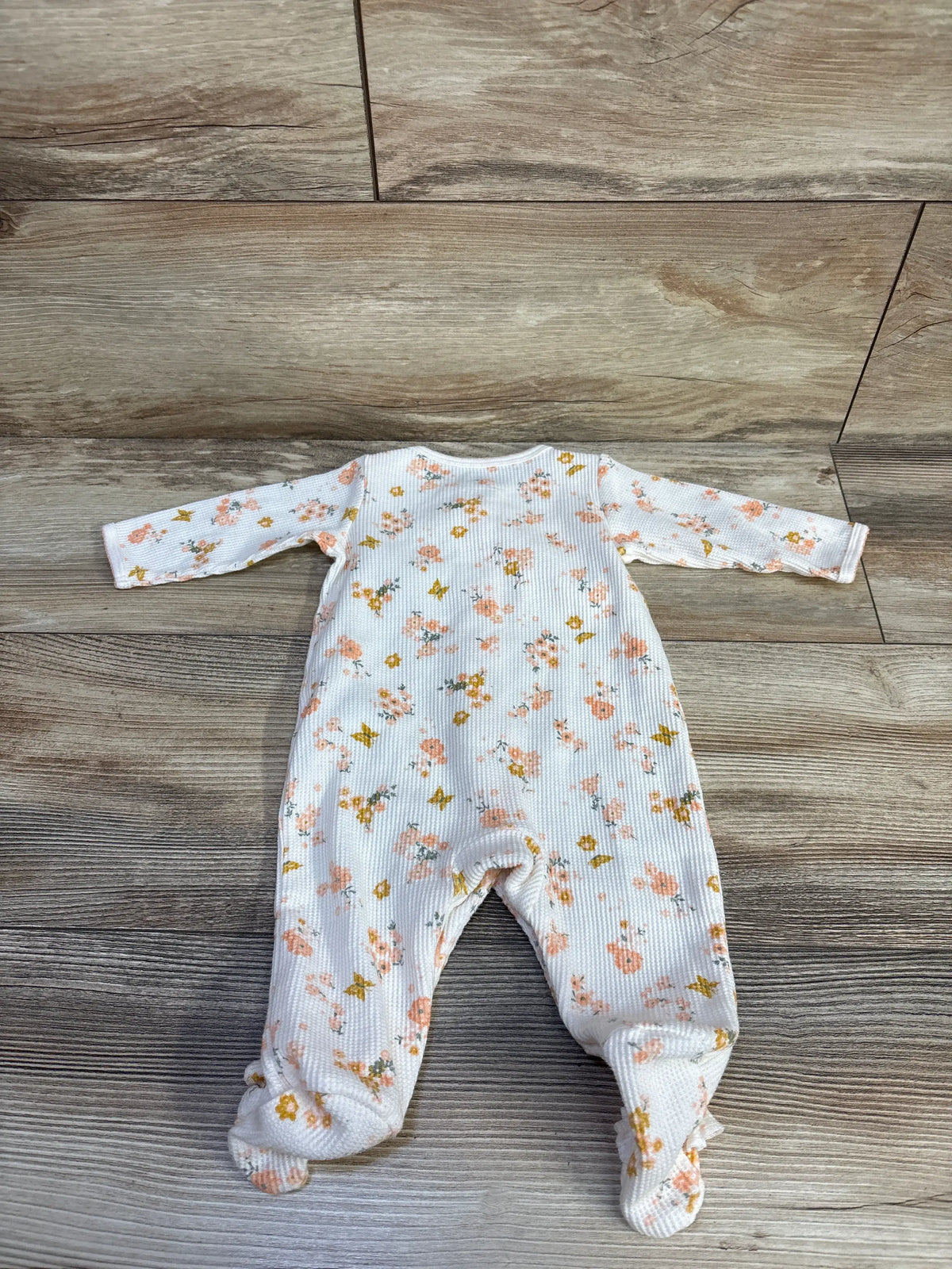 Carter's cream floral waffle knit snap sleeper for babies laid on a wooden surface