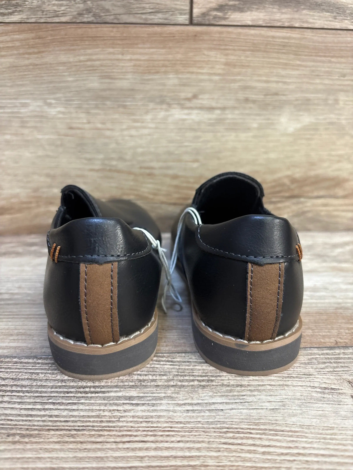 Rear view of black and brown kids dress shoes on wood background