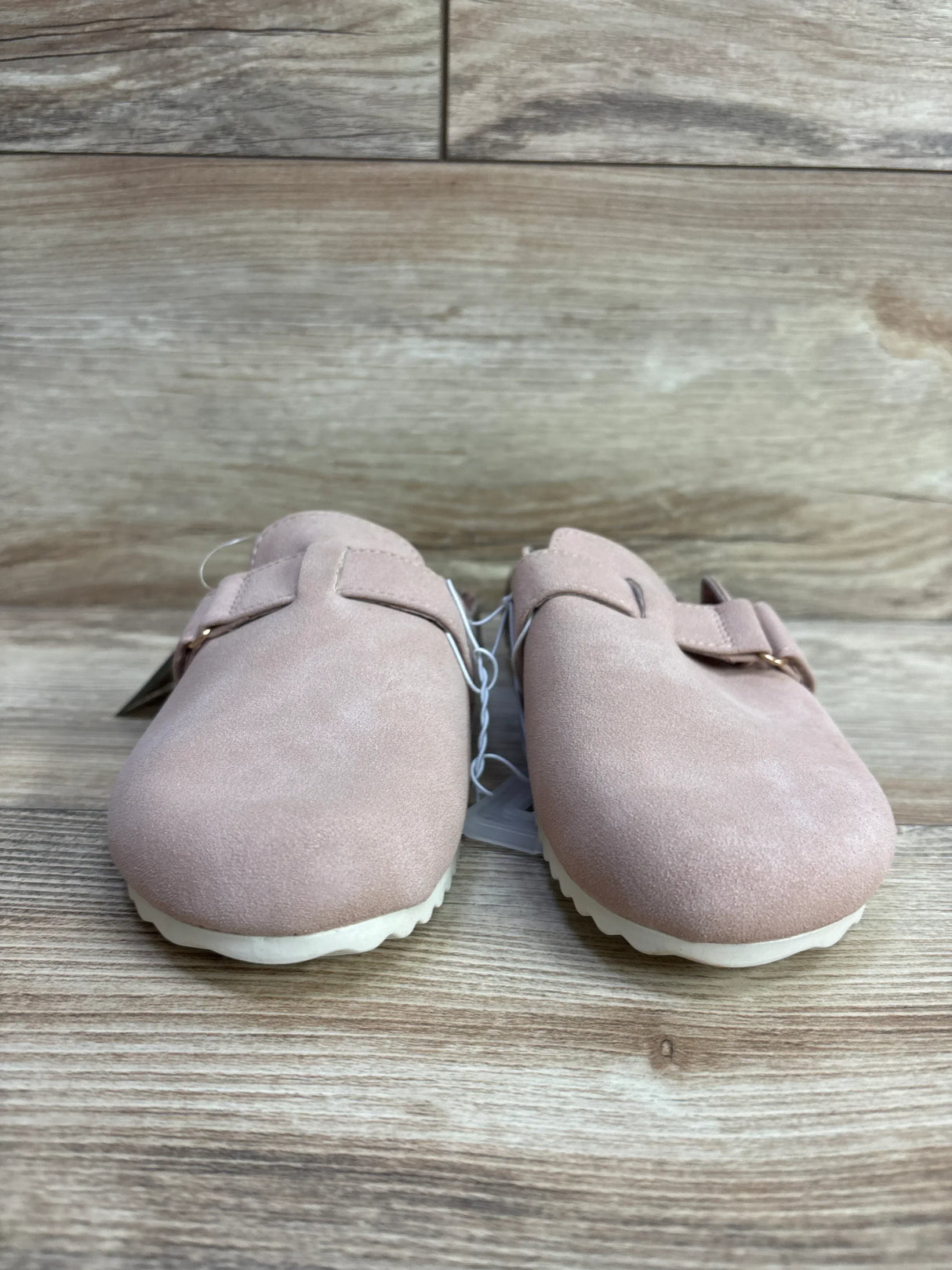 Front view of Cat & Jack Perry clogs in blush showing suede upper, adjustable buckle and white ridged sole on wooden floor