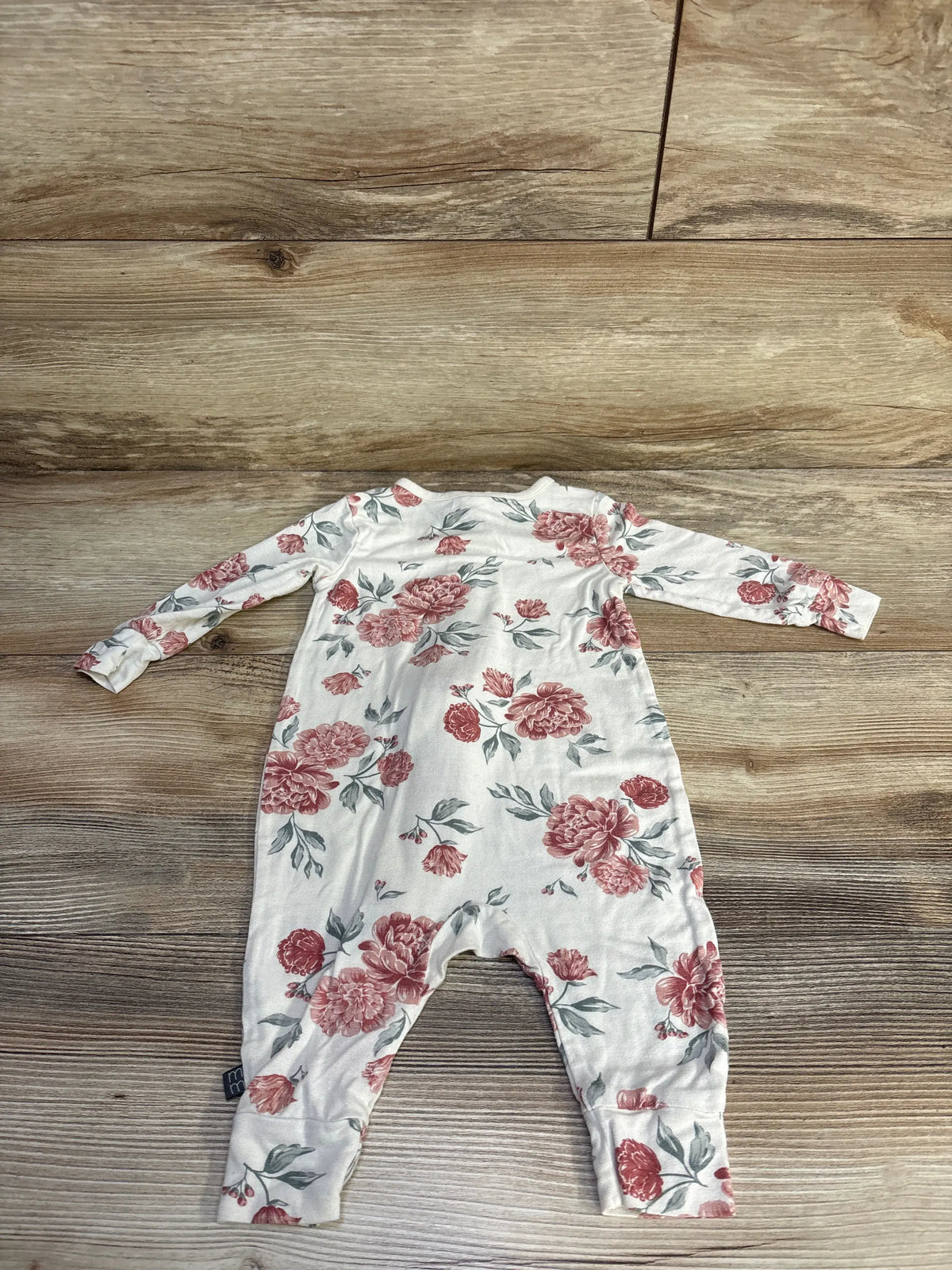 Front view of Modern Moments floral footless sleeper showcasing ivory fabric, long sleeves, and floral pattern on a wood-look background