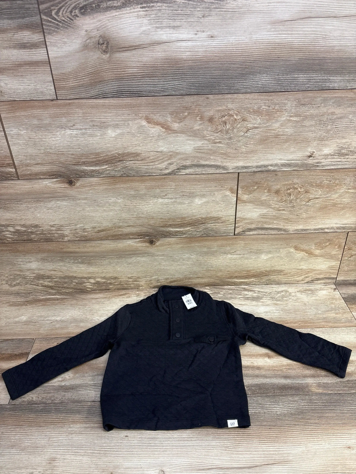 Black long sleeve GAP kids shirt with buttons on wood background