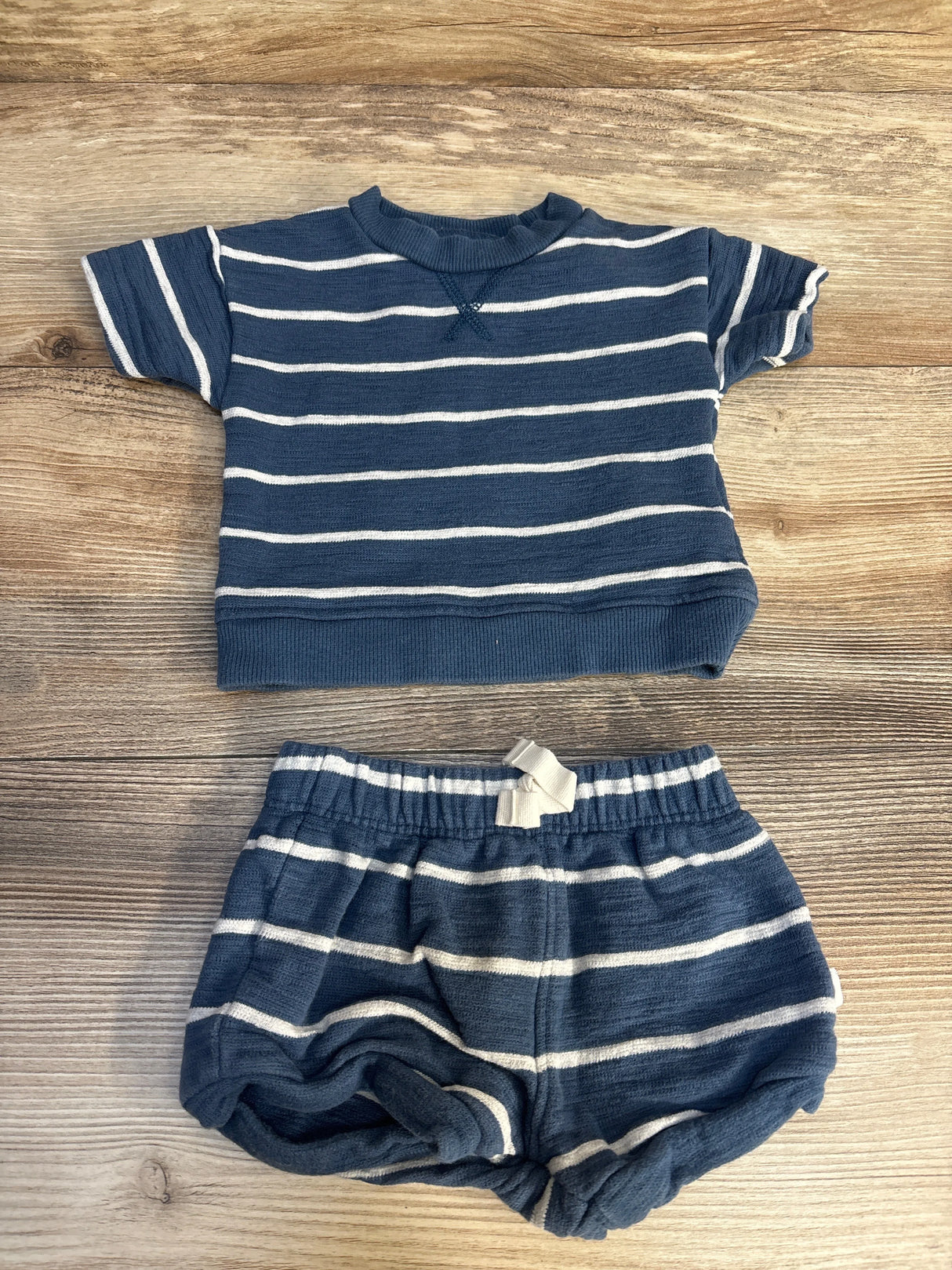 Blue and white striped baby outfit with short sleeve shirt and shorts on wooden background