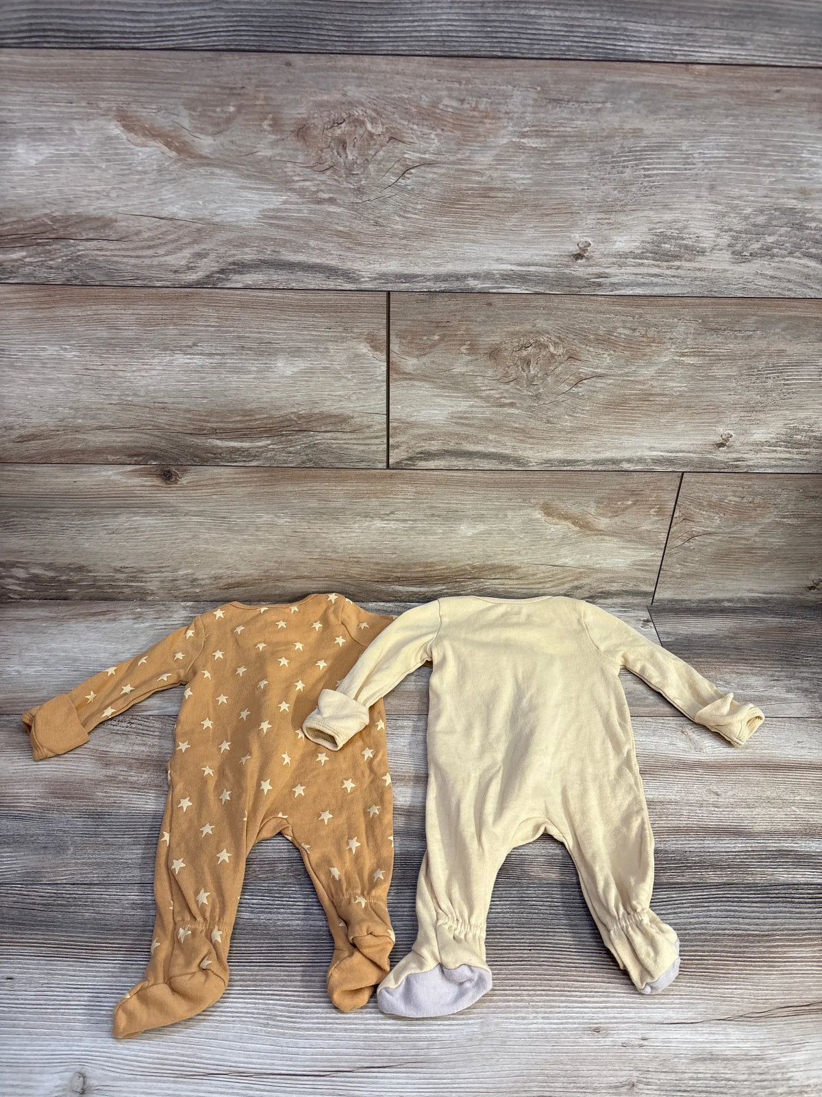 Front view of Cloud Island two pack sleepers showing yellow and star patterned sleepers on a wood look background