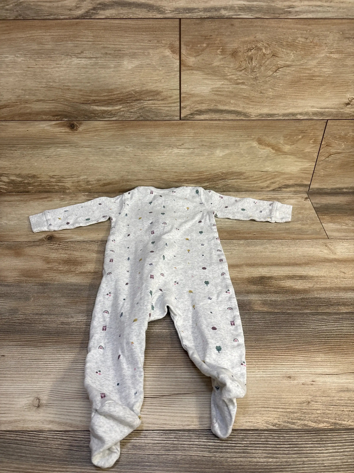 Flat lay of Little Planet organic footed sleeper (9 months) showing light heather grey fabric with small multicolor nature prints on wood floor