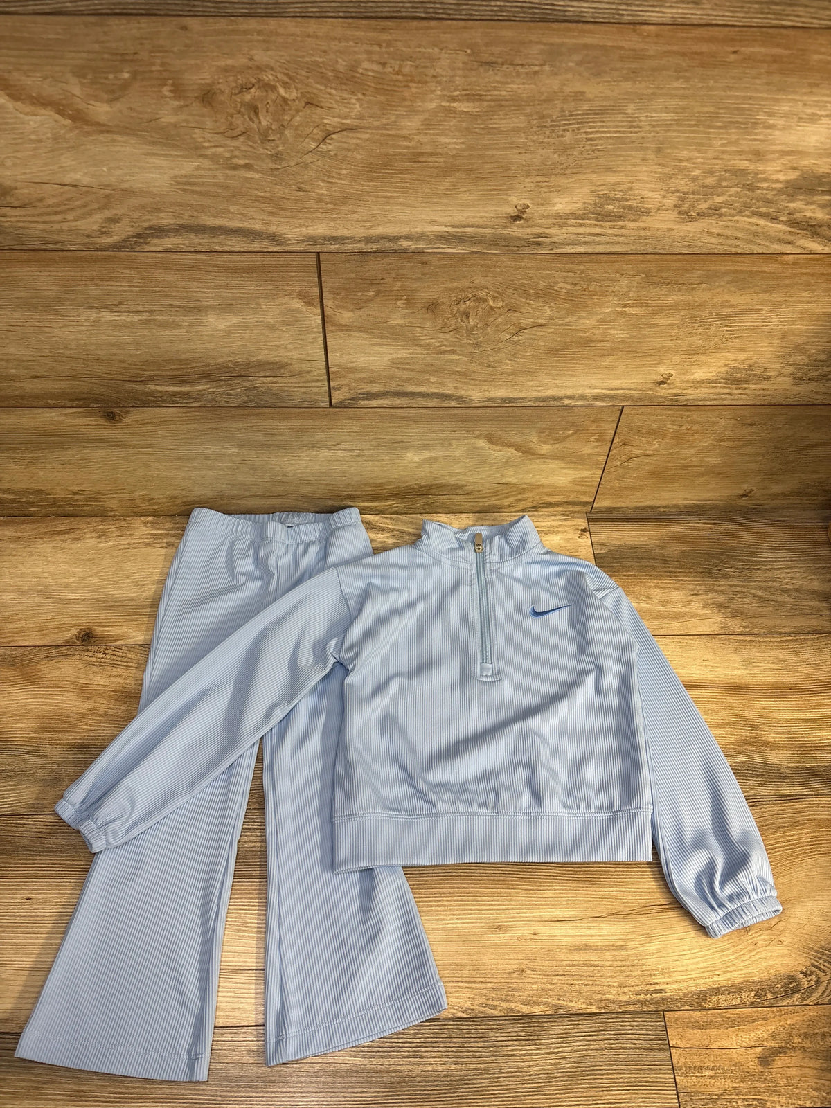 Light blue ribbed half-zip jacket and flare pants set by Me n Mommy To Be on a wood floor