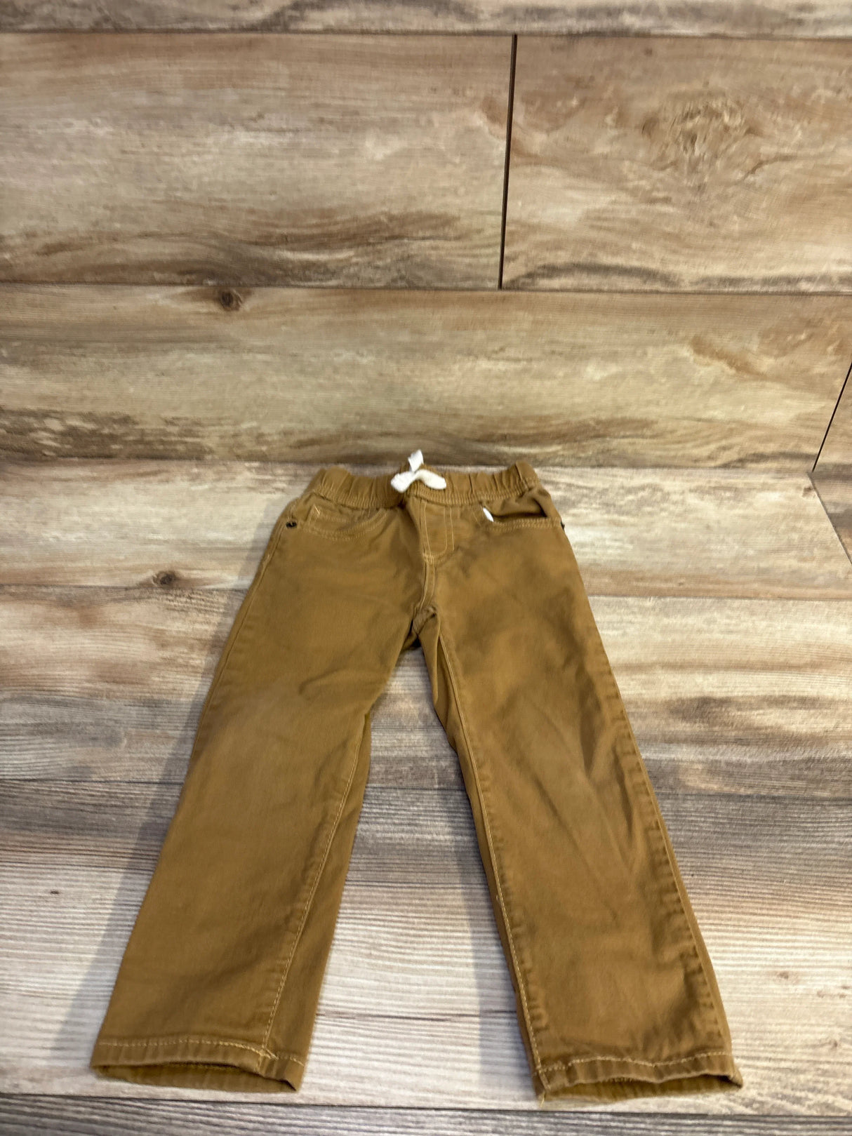 Flat lay, front view of Baby Gap brown toddler drawstring pants, size 3T, showing elastic waistband with white drawstring on wood background