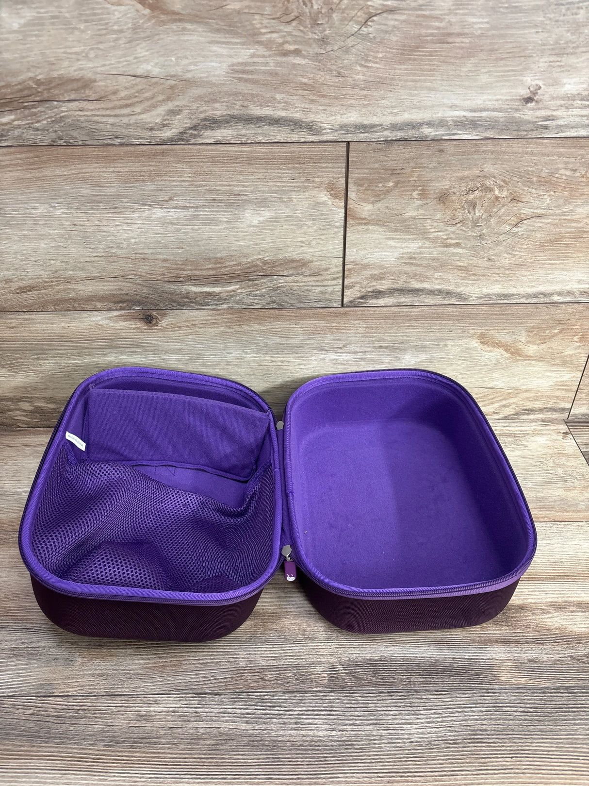 Top view of Hermitshell case in purple for Spectra breast pump showing open interior with mesh pocket on wood floor