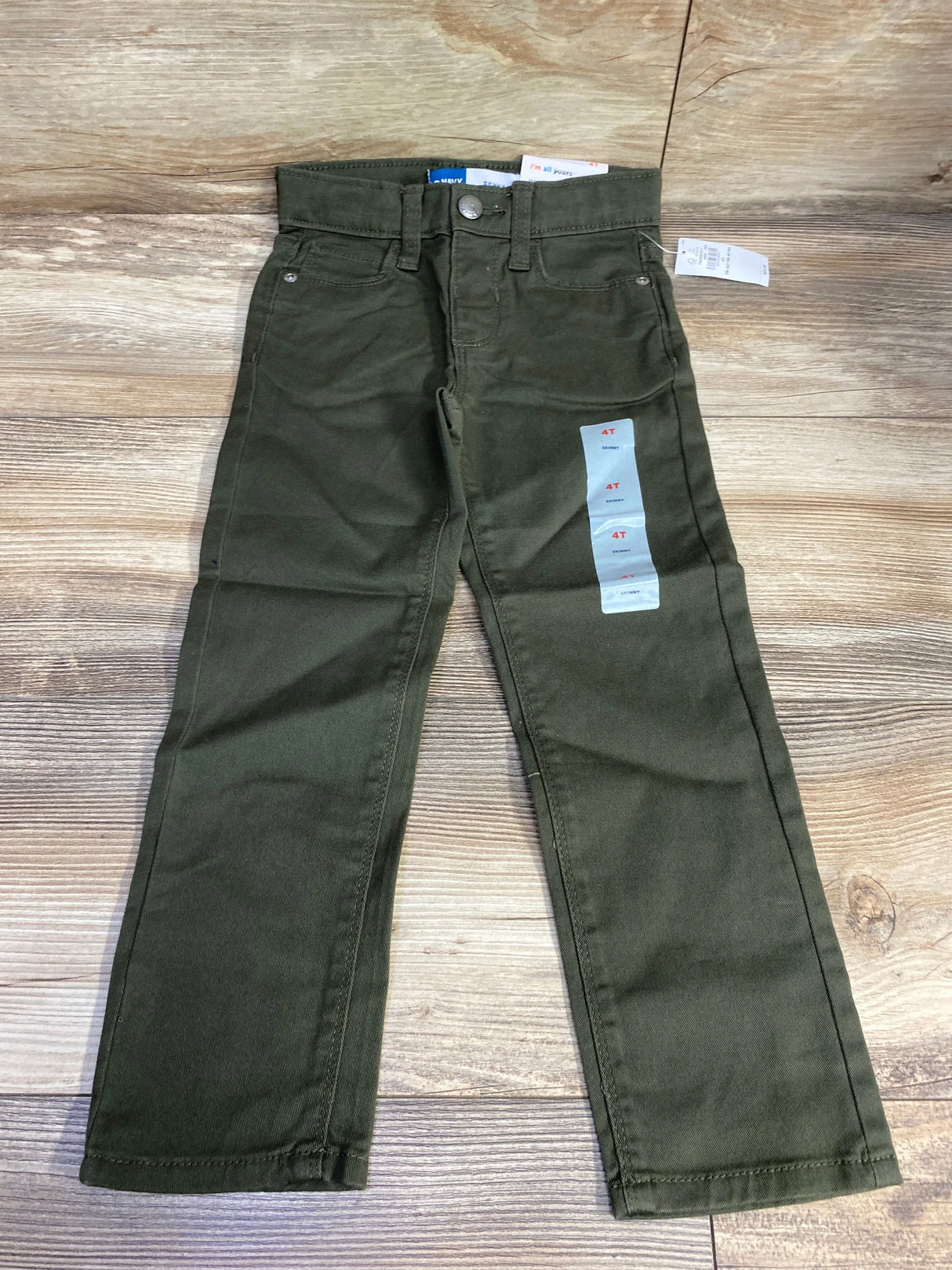 Olive green toddler pants with tags, size 4T, laid flat on wooden floor