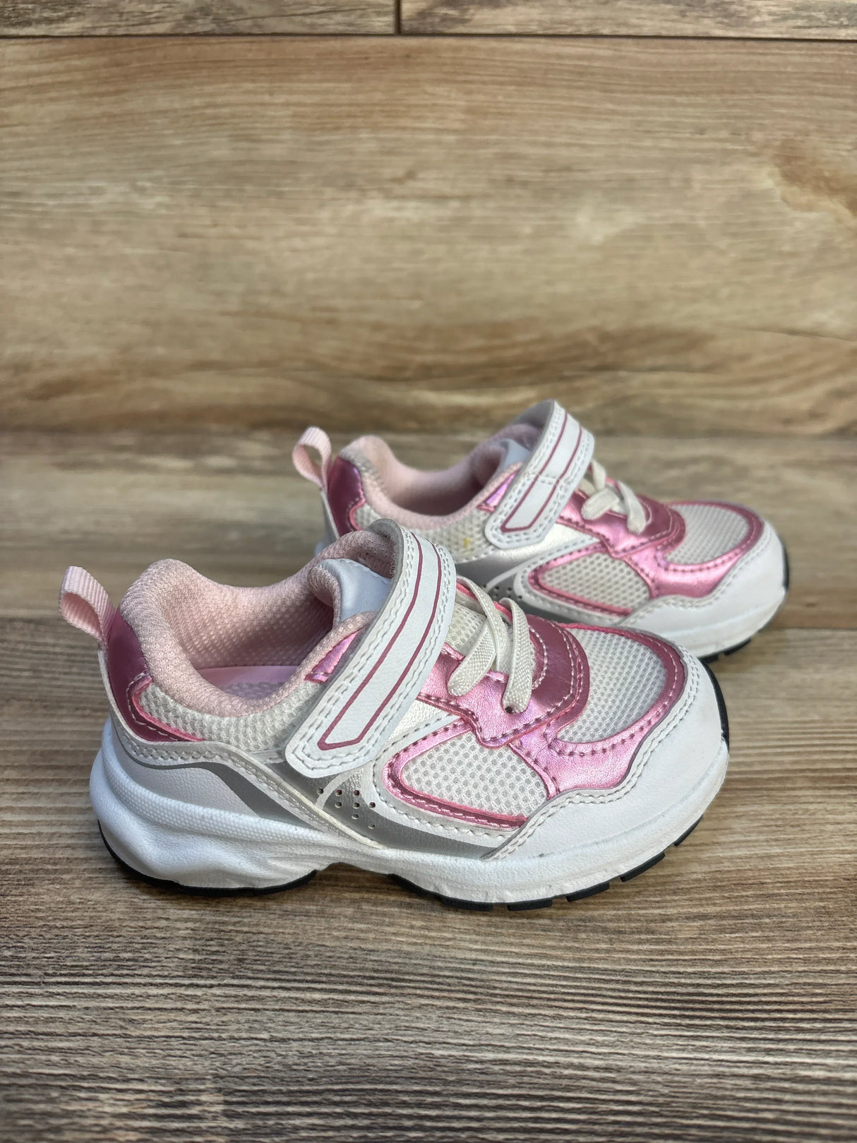 Pink and white toddler sneakers with Velcro straps on wood background