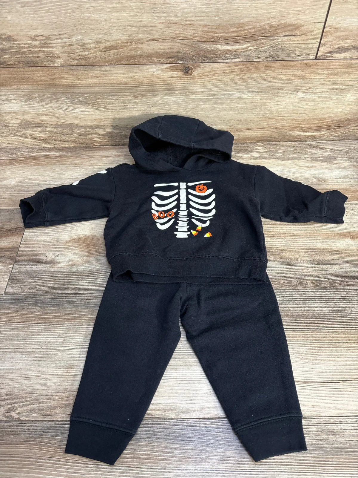 Front view of Child Of Mine 2pc black skeleton hoodie and joggers with white skeleton and BOO graphics on wood