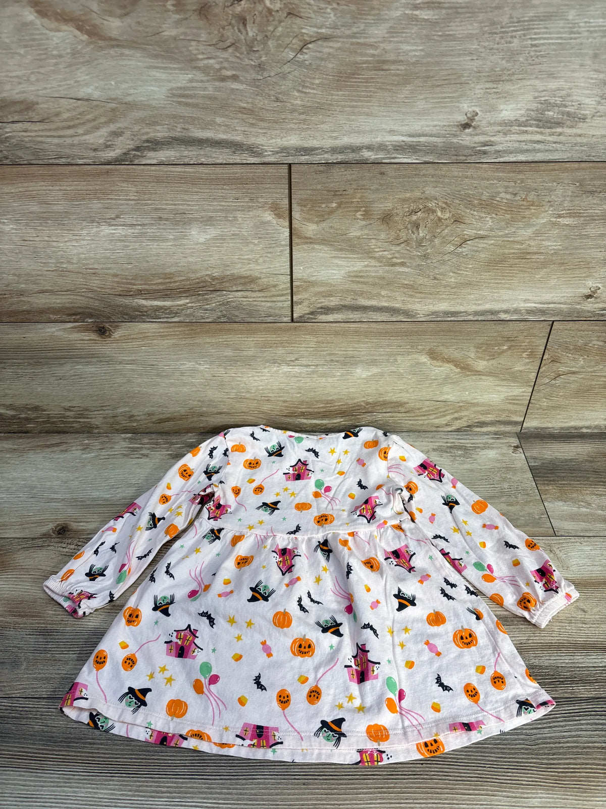 Front view of Old Navy Halloween icon long sleeve dress with pink Halloween print, puffy sleeves, and seamed waist on wood