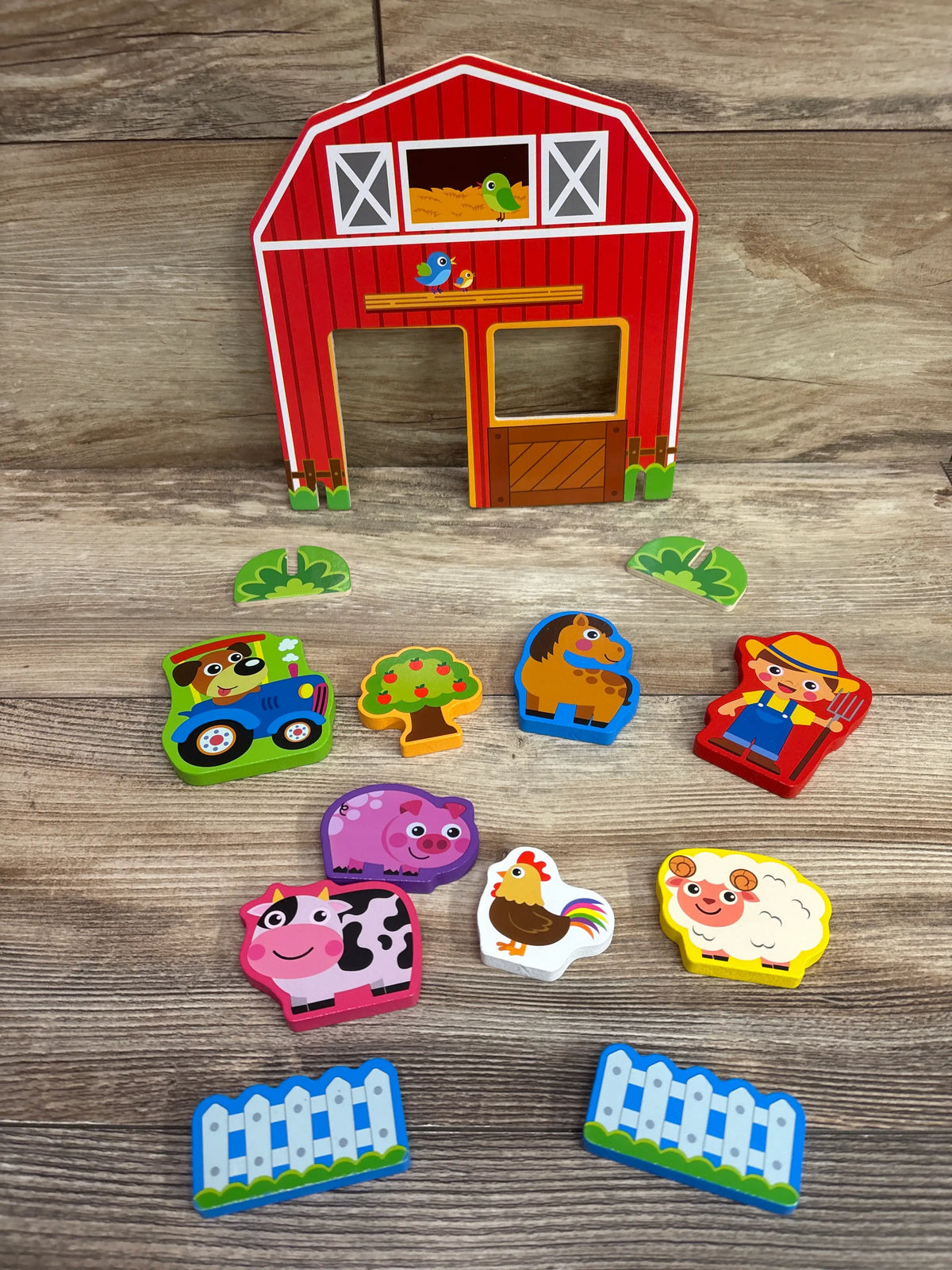 Front view of Matty’s Toy Shop Deluxe Wooden Farm Playset 13pc showcasing red barn, farm animals, tractor, and fences