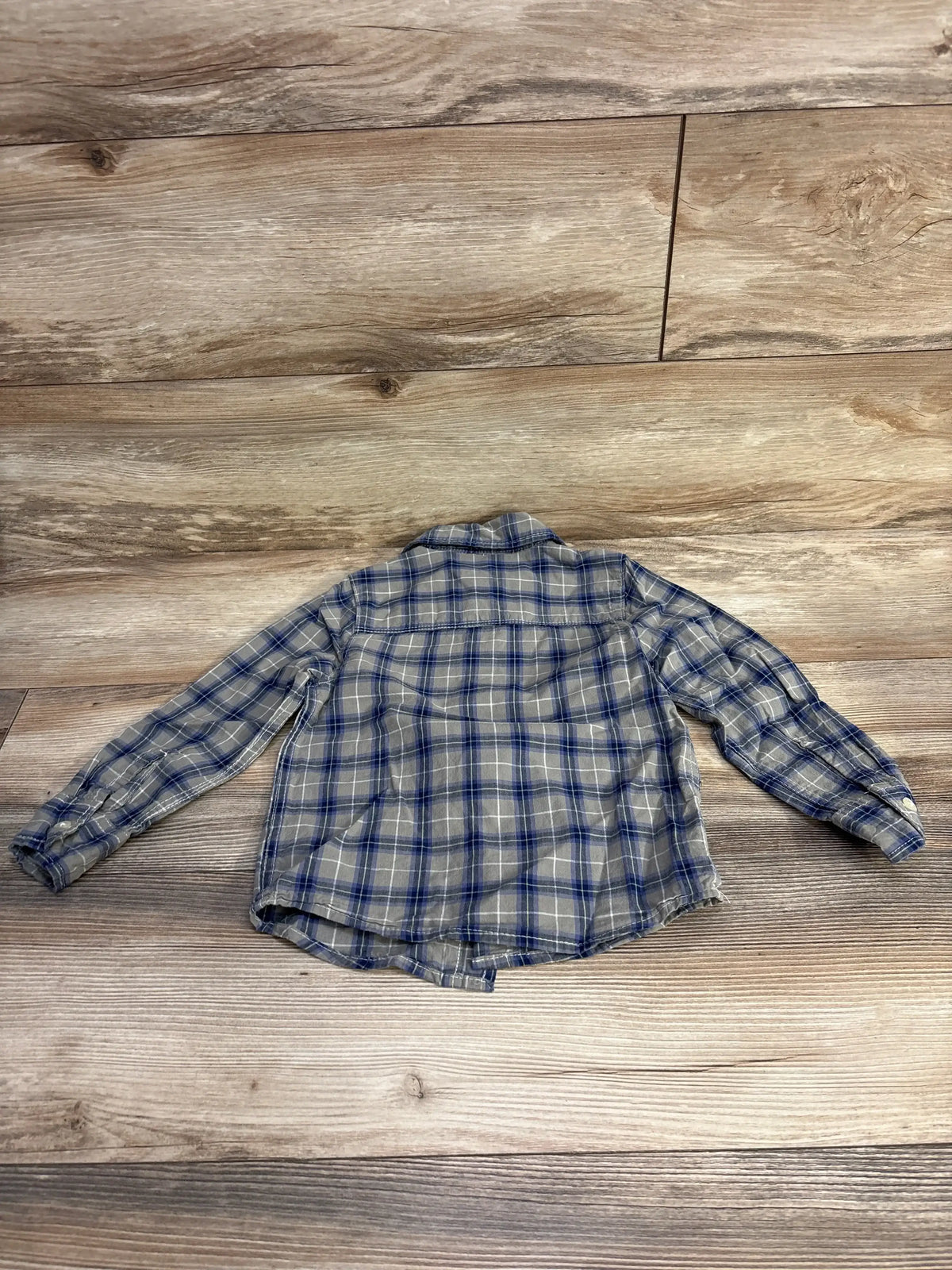 Back view of toddler OshKosh green and blue plaid long-sleeve button-up shirt showcasing back yoke and curved hem on wood floor