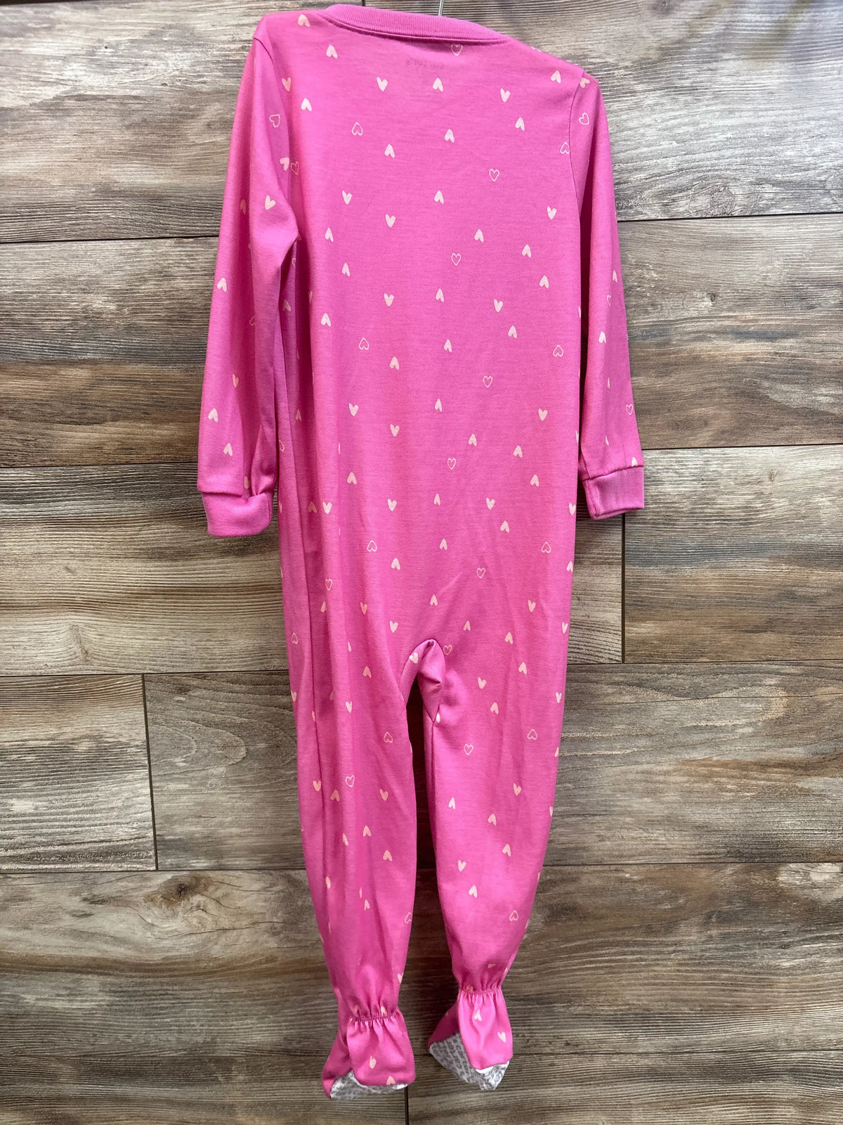 Pink Just One You toddler sleeper with small white heart print on a wood background