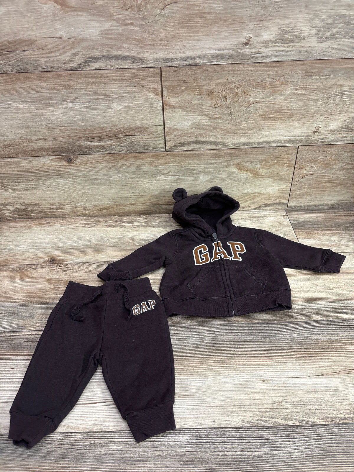Flat lay of Baby Gap two-piece zip-up hoodie and joggers set in black with GAP logos and rounded-ear hood