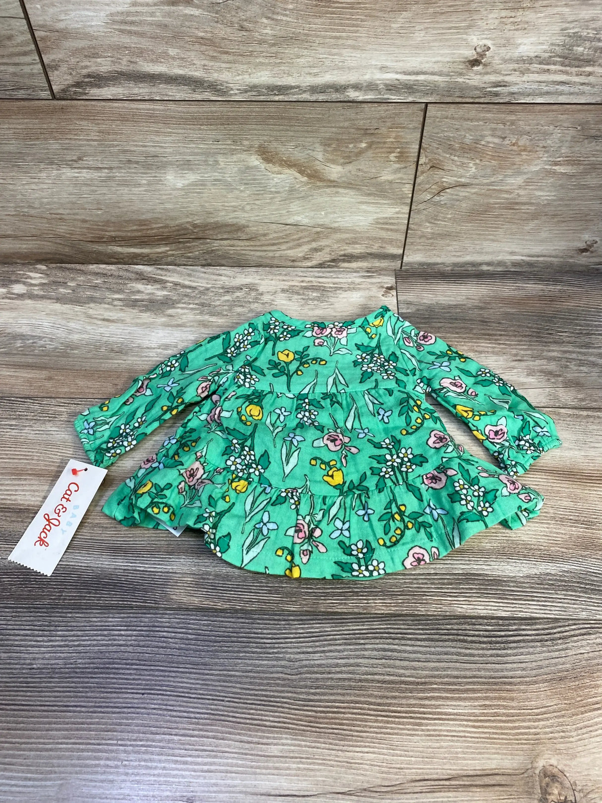 Flat lay of Cat and Jack newborn Henley dress and bloomers, green floral print with tiered ruffle on wood surface