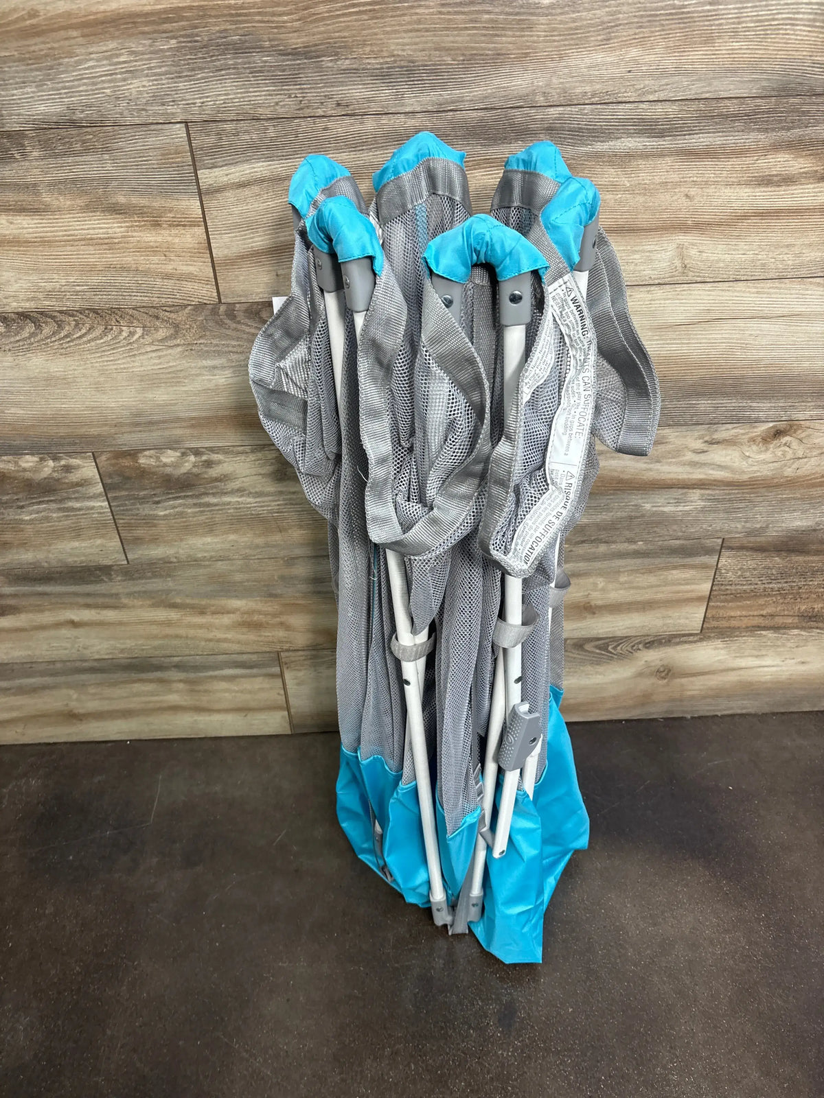 Front view of Regalo My Play portable 6-panel play yard showcasing gray mesh walls and teal trim on wood flooring