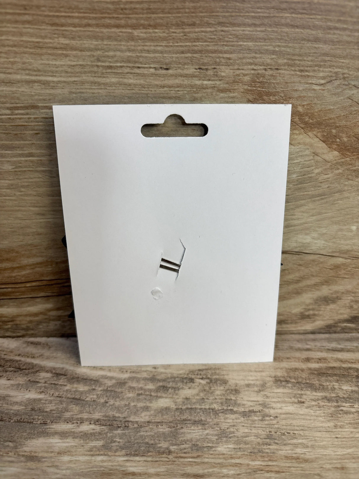White retail tag with hang hole on wood surface, for kids or maternity items