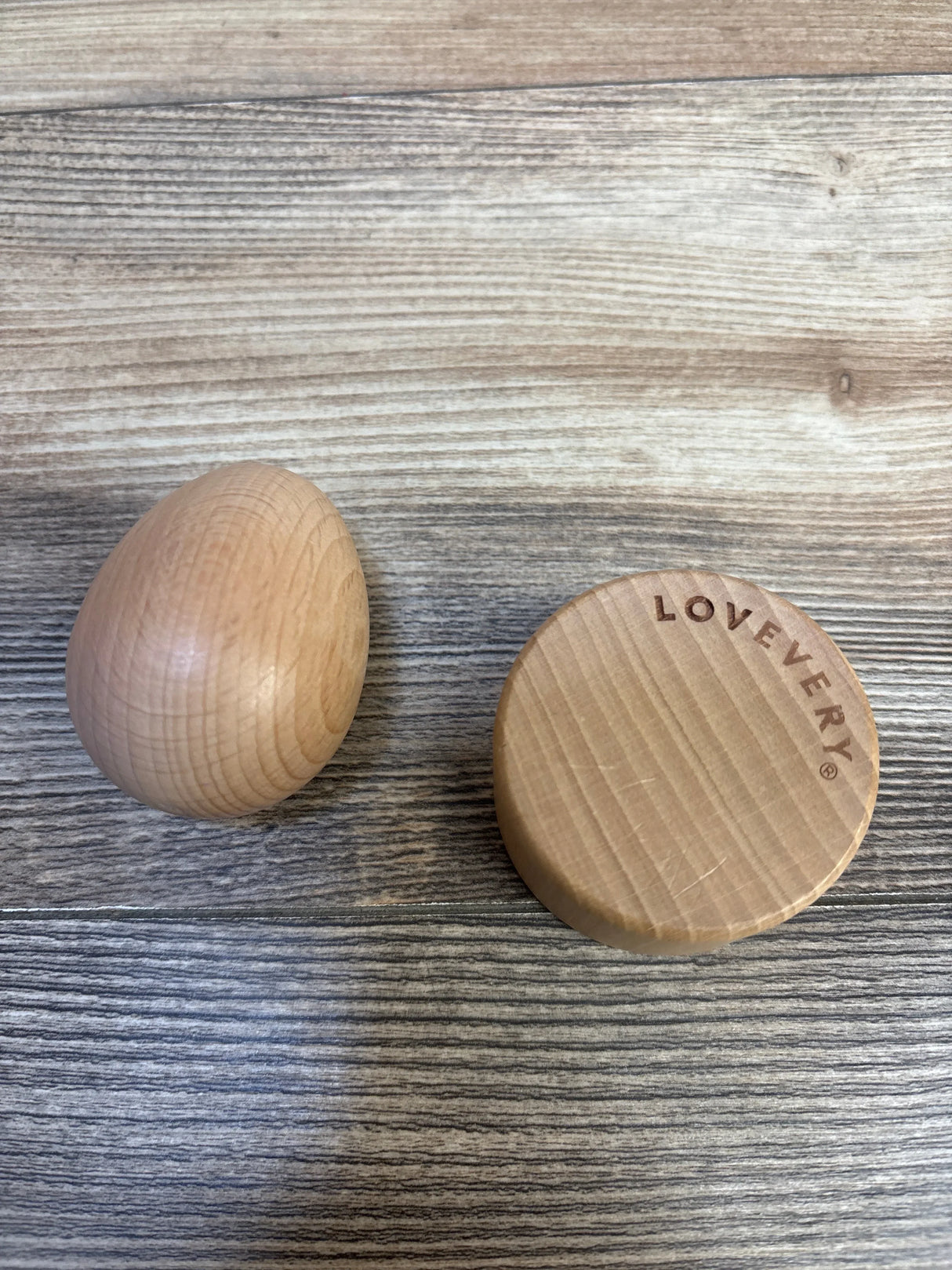 Top view of Lovevery Montessori Egg Cup and egg showing engraved LOVEVERY logo and smooth wood finish