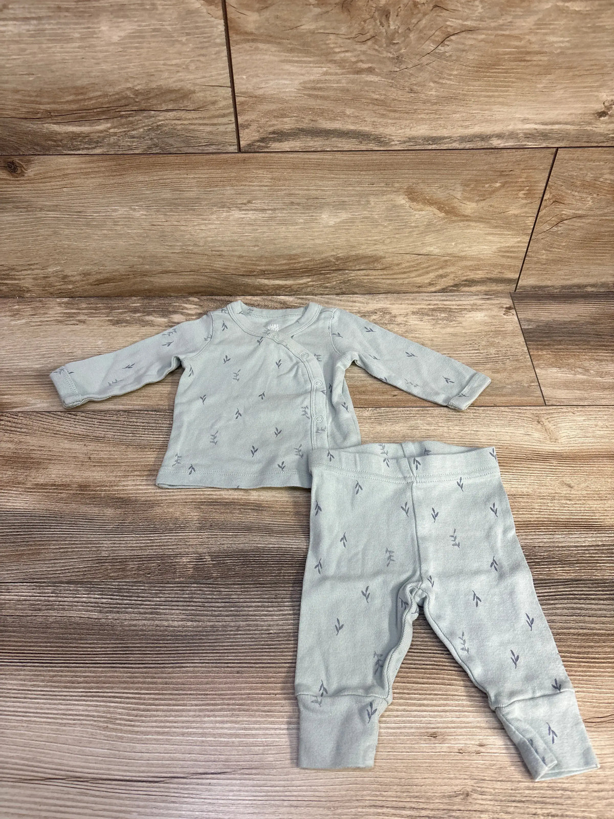 Flat lay of Just One You green two piece kimono shirt and pants set with wrap shirt and small leaf pattern on wood flooring
