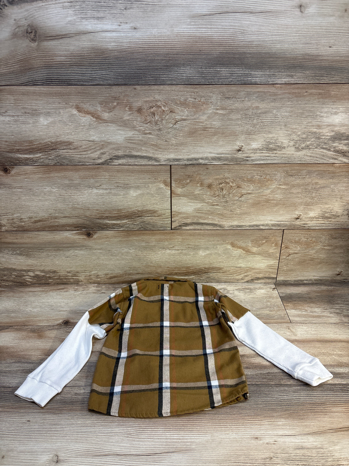 Back view of DKNY toddler plaid button-up long-sleeve shirt (caramel, size 4T) showing white layered sleeves on wood floor