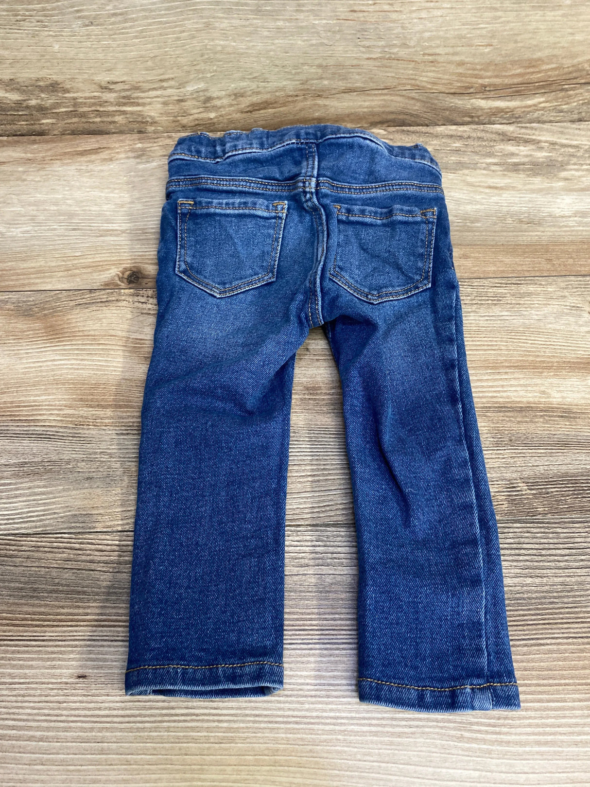 Back view of blue Old Navy toddler skinny jeans 18-24 months showing elastic waistband and back pockets on wood background